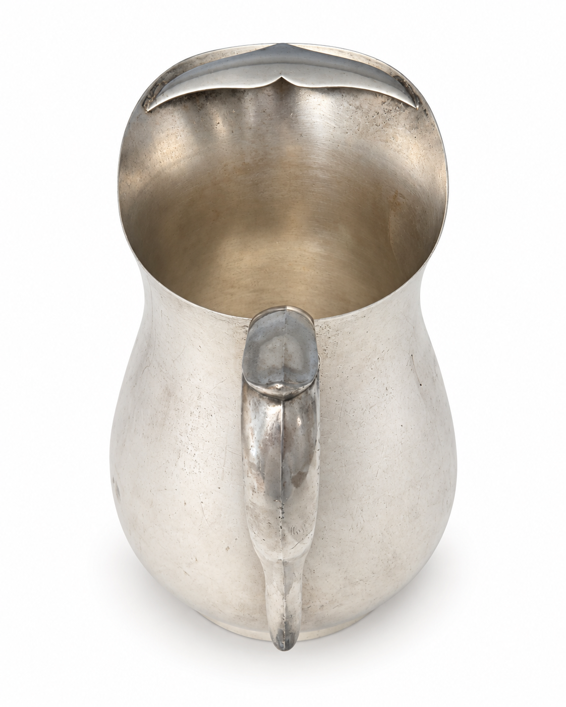 Elevated view inside a silverplate pitcher showing the ice guard, interior finish, and handle.
