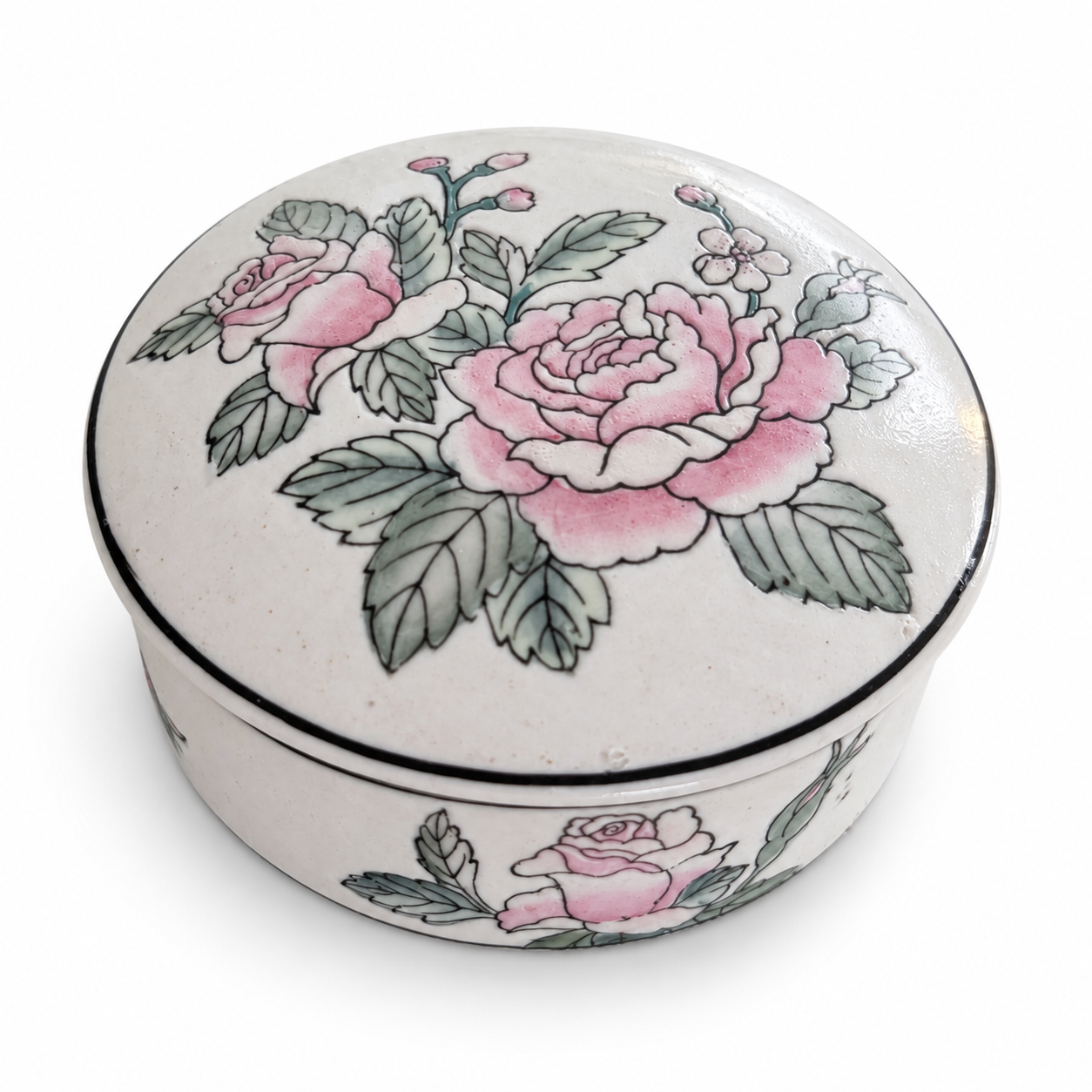 Close view of the pink flowers and black edging on a porcelain box in a colorful vanity setting.