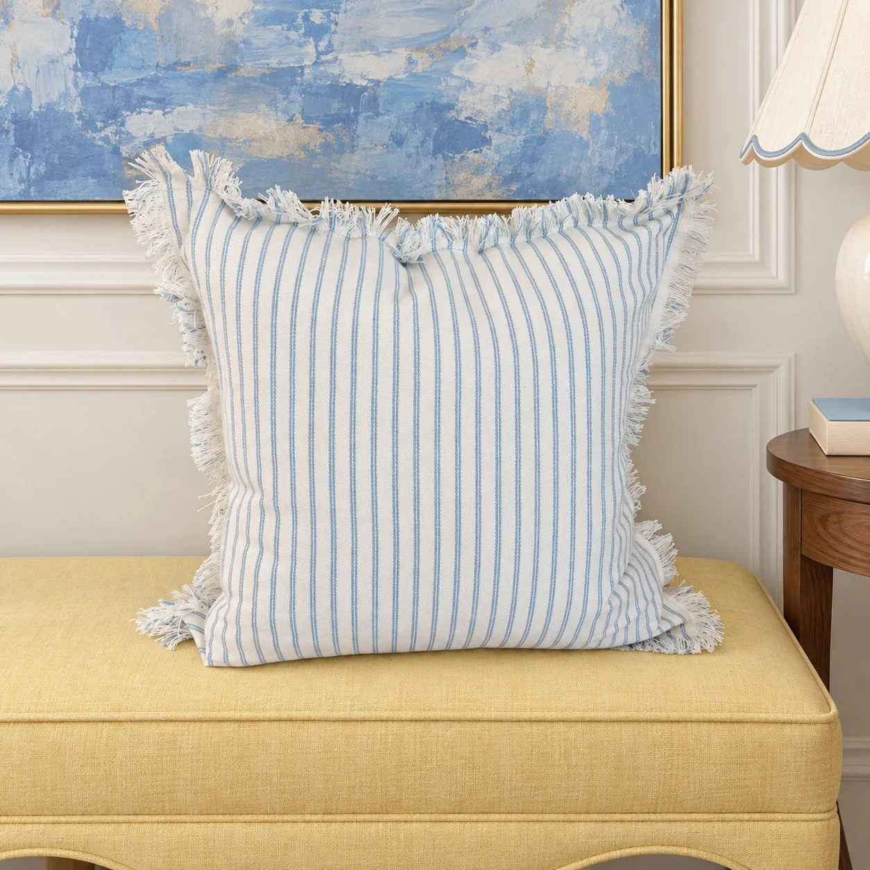 Fringed stripe pillow on a butter-yellow upholstered bench.