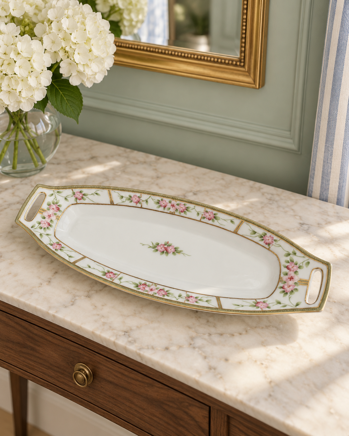Nippon porcelain tray with pink flowers, green leaves, gold trim and pierced handles on a white background.