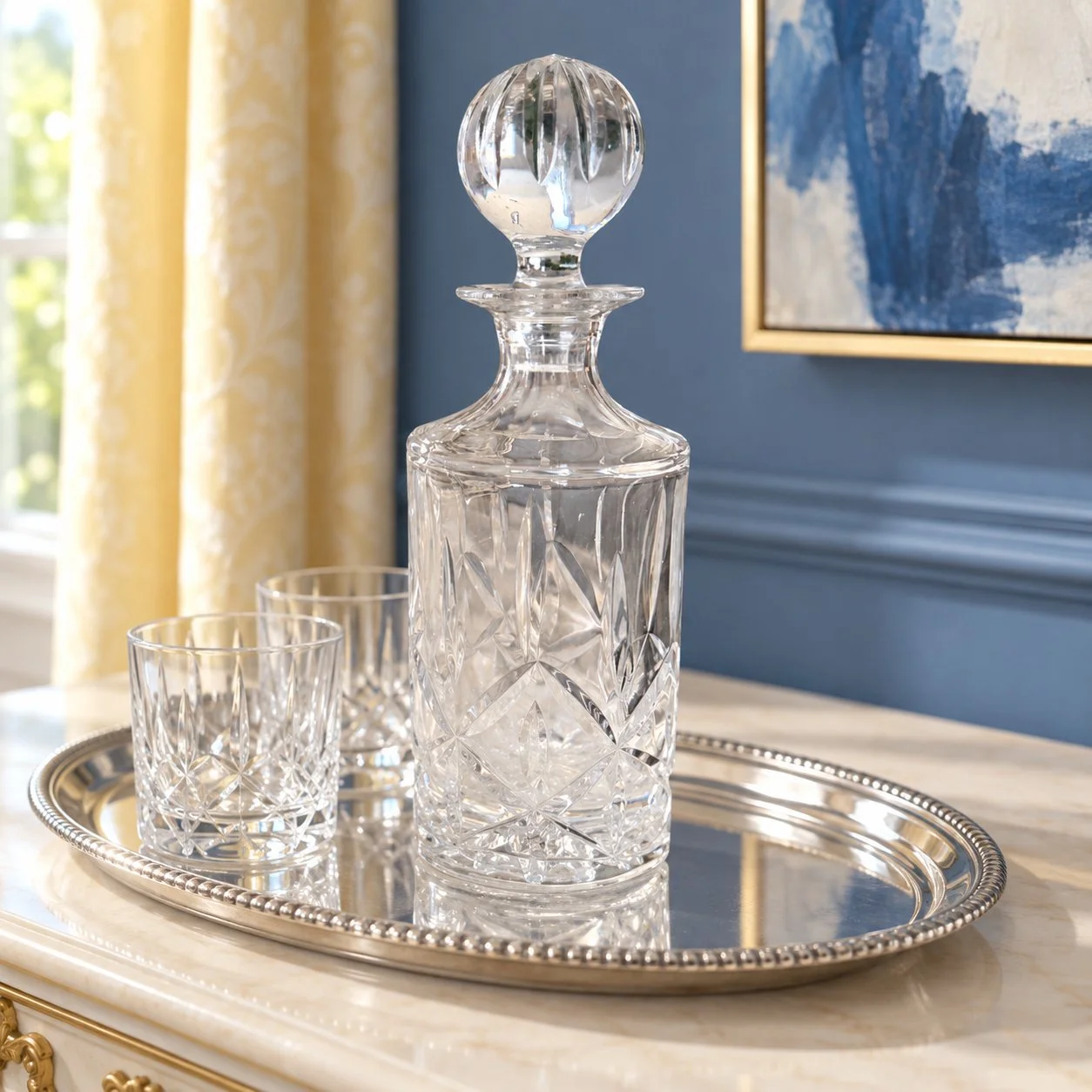 Clear glass decanter on a silver tray in a French-blue interior.