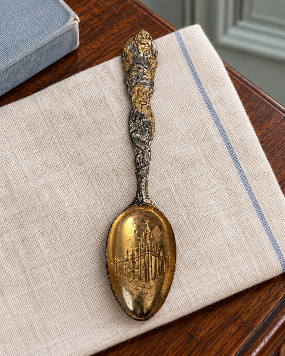 Angled view of the St. Louis souvenir spoon showing its decorated bowl and dragon handle against ivory linen.