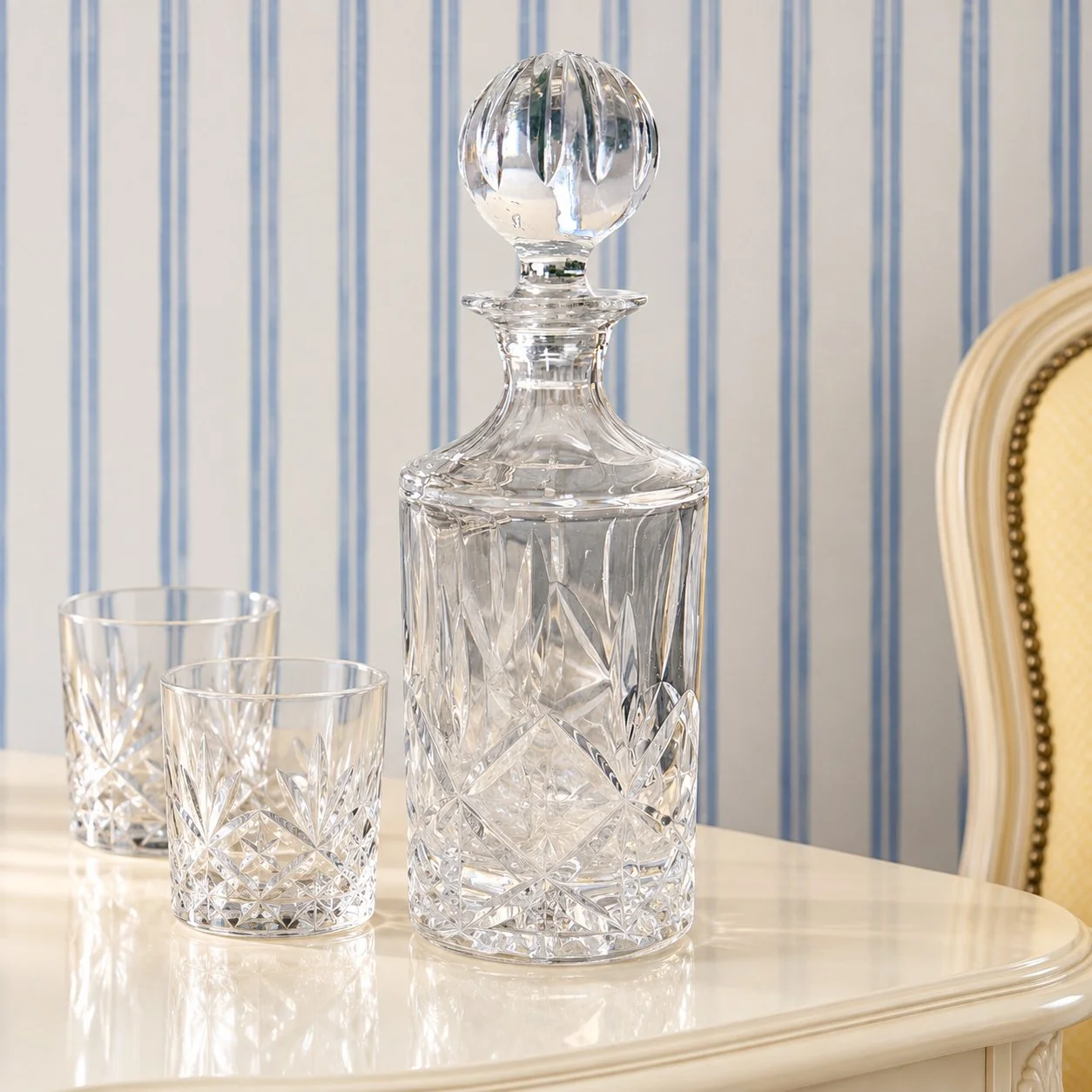 Faceted decanter displayed on an ivory cabinet with a pair of glasses.