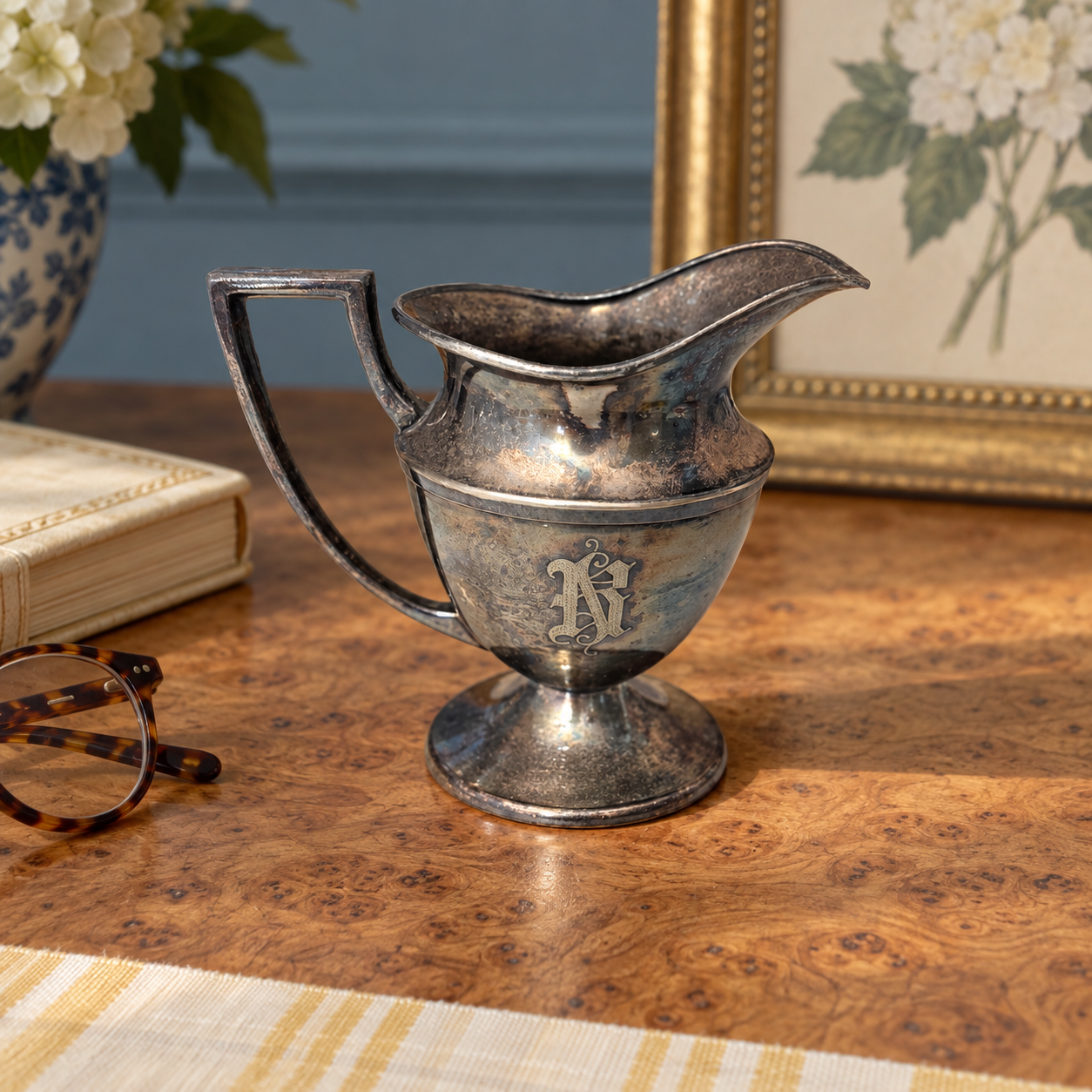 Engraved monogram on the front of the tarnished silver-tone creamer.