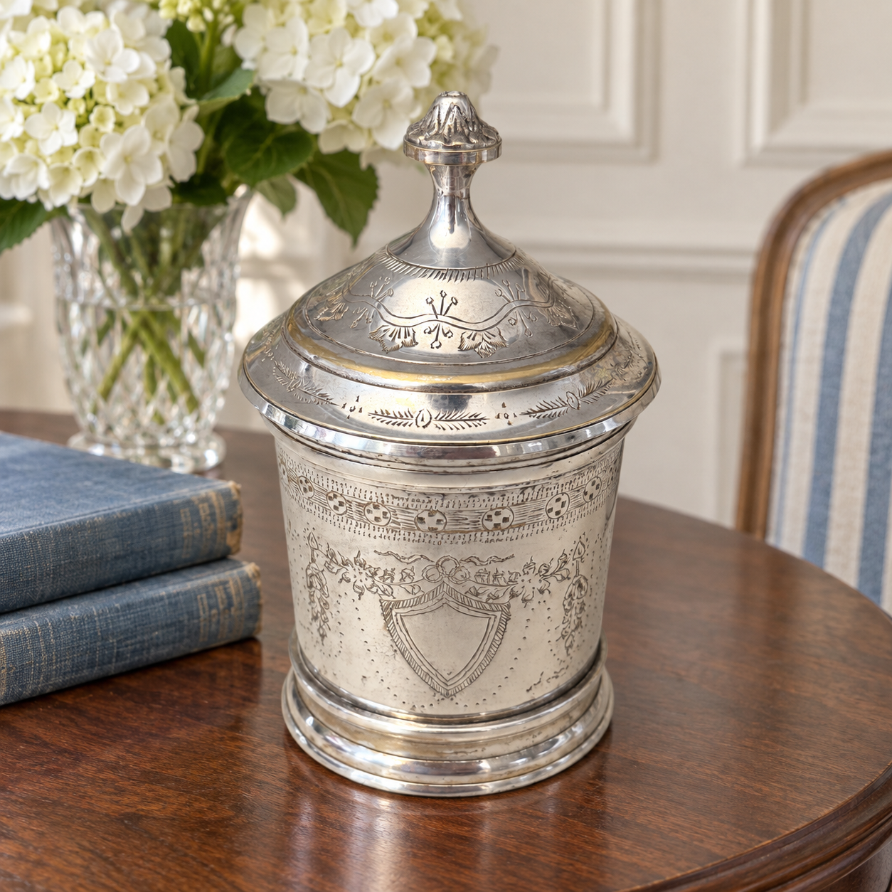 Engraved shield framed by a bow and garlands on the decorative metal jar.