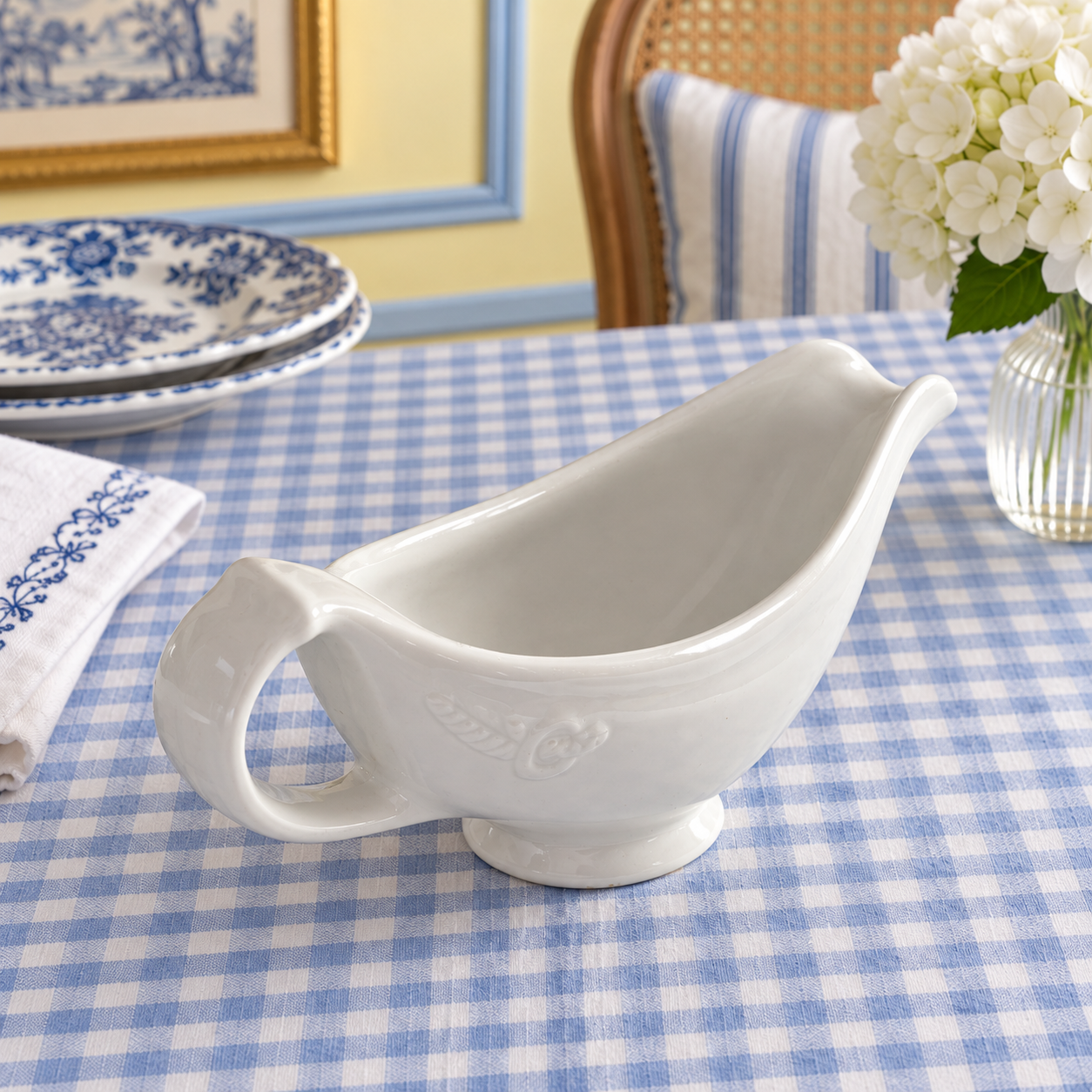 Hall gravy boat viewed from above beside blue patterned plates on checked table linen.