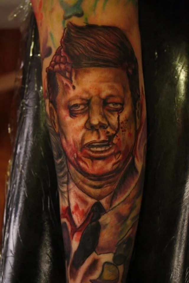 Tattoo of a distressed man's face with disheveled hair and elf-like ears, showing a pained expression, on a person's arm.