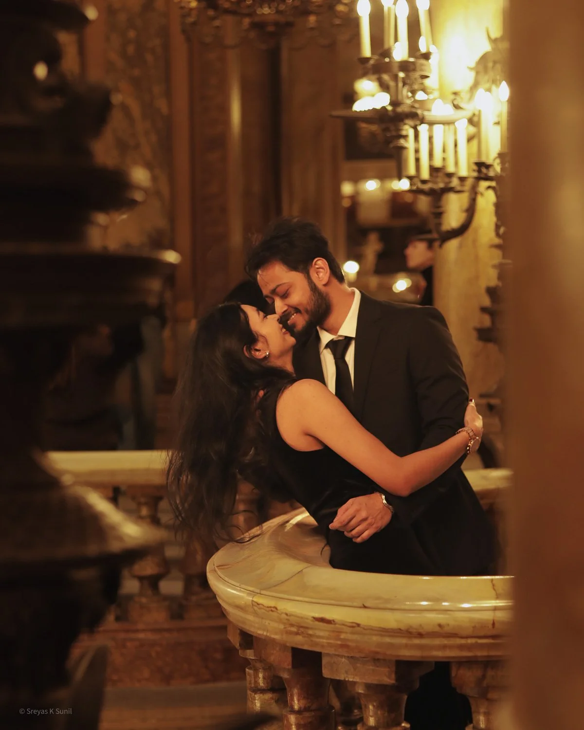 A romantic couple dancing closely in a warmly lit, ornate, vintage interior with chandelier lighting. Paris Opera