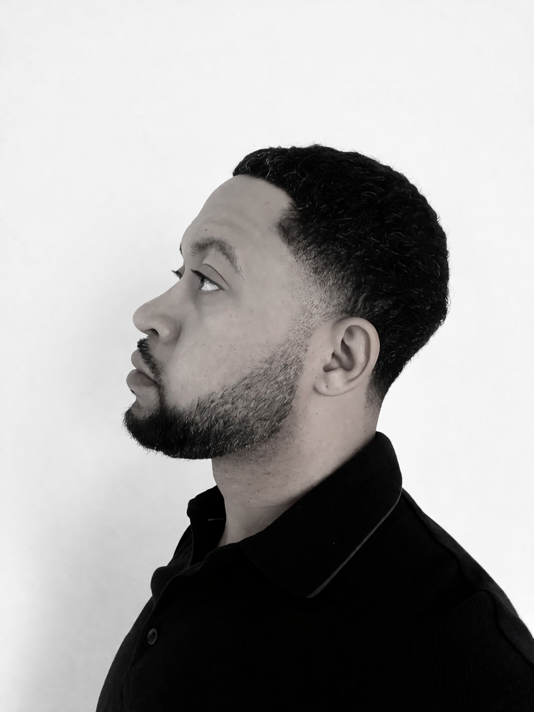 Black and white side profile portrait of a man with a fade haircut and beard.