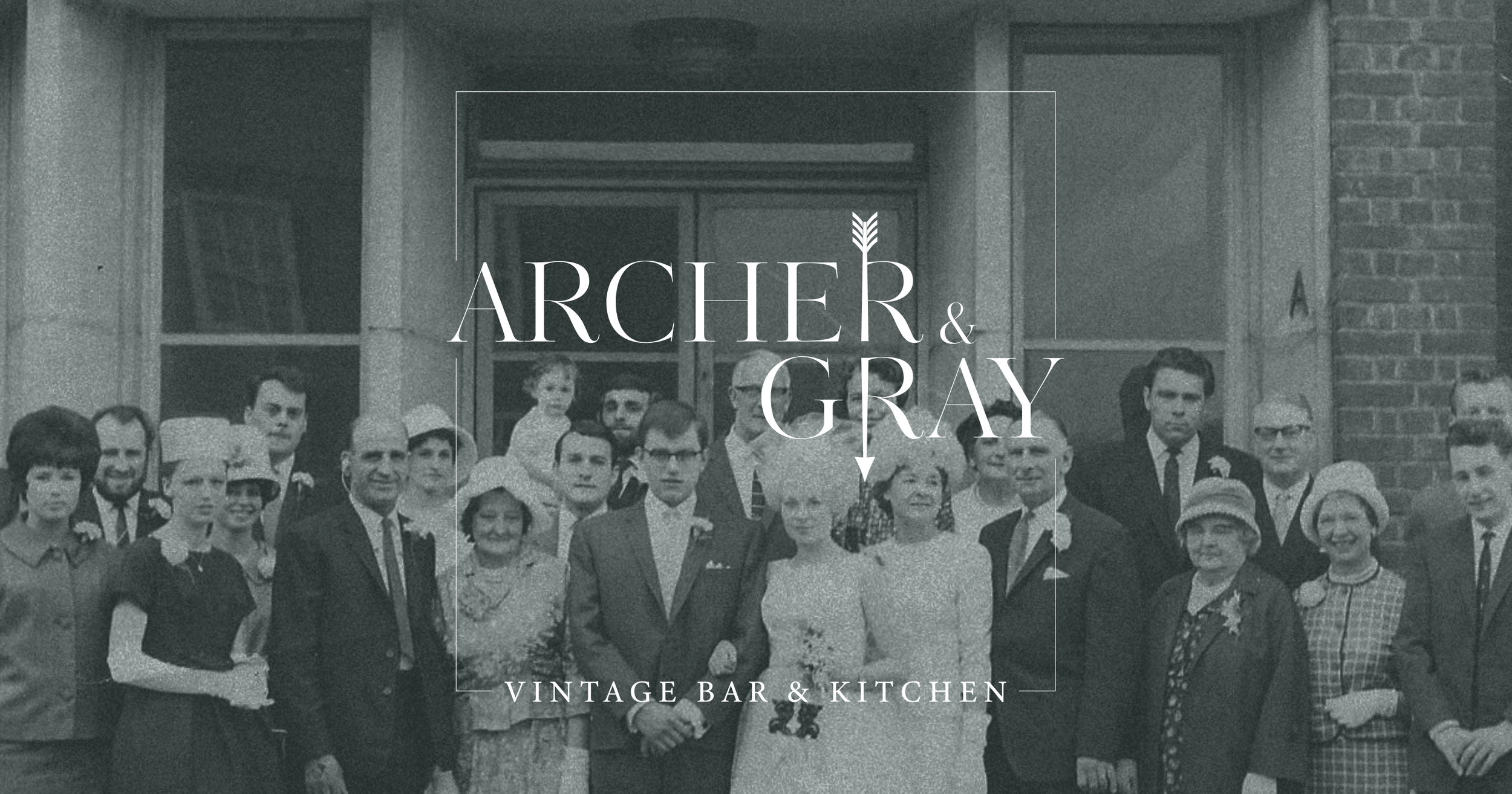 Black and white vintage photo of a group of people gathered outside a building with a sign for "Archer & Gray, Vintage Bar & Kitchen." The group is dressed in mid-20th-century clothing, with some women wearing hats and men in suits.