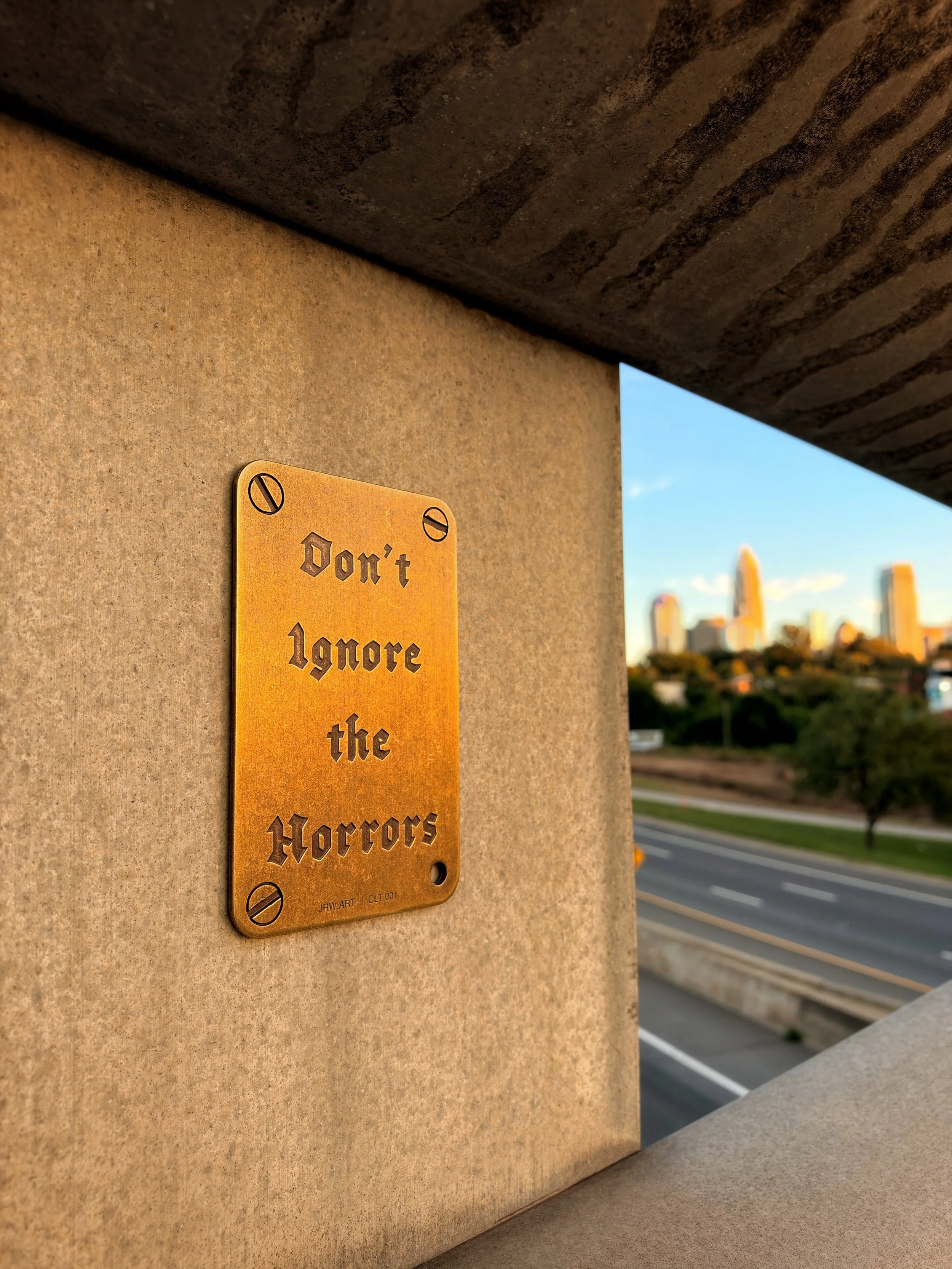 PUBLIC STUDY - CLT 001

The first public installation of Don't Ignore the Horrors&trade; now overlooks the Charlotte, NC skyline.

This plaque serves as a quiet warning not to grow comfortable with cruelty. Don't ignore the horrors within the authori