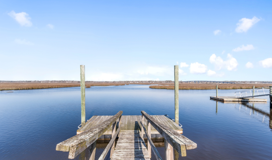 Wooden dock at El Sol extending over calm marsh water at Sunset Beach, NC.
