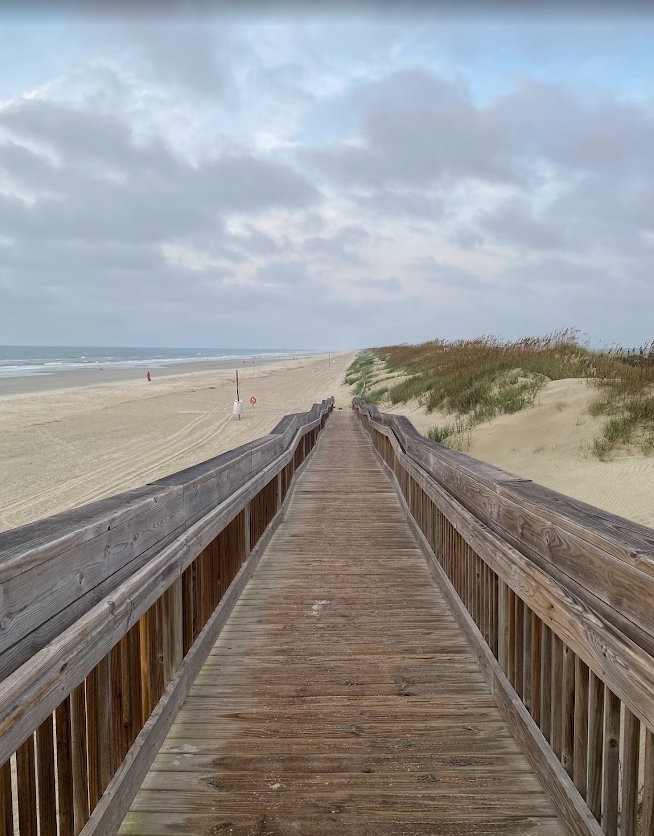 Wooden boardwalk leading through dunes and sea grass to the 40 street beach access at Sunset Beach, North Carolina.