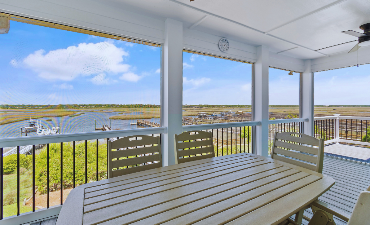 Screened porch at El Sol overlooking the marsh, with a table set for outdoor dining