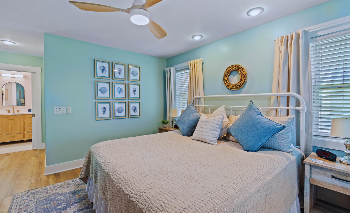 Bedroom at El Sol with a king bed, beige quilted bedspread, and coastal-themed wall art.