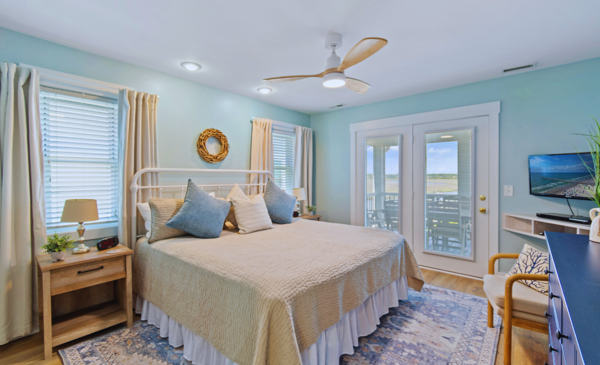 Primary bedroom at El Sol with a king bed, ceiling fan, and French doors to the waterfront balcony.