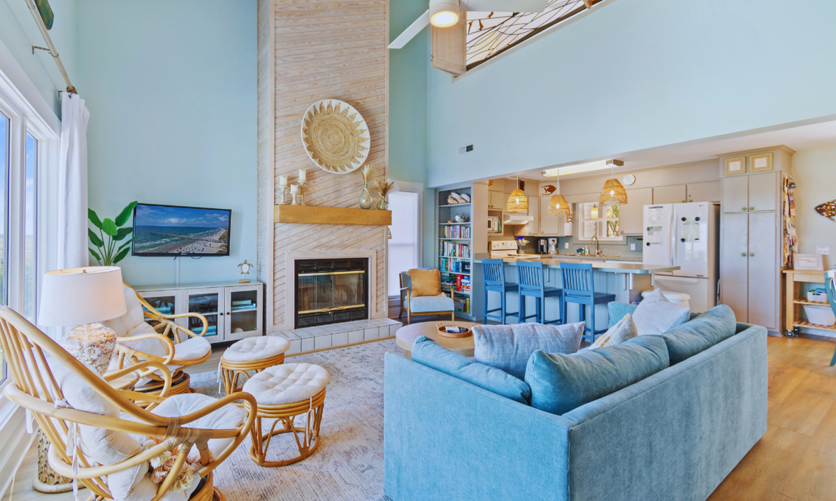 Open-concept living room and kitchen at El Sol with light blue walls, a blue sofa sofa, fireplace and a kitchen island.