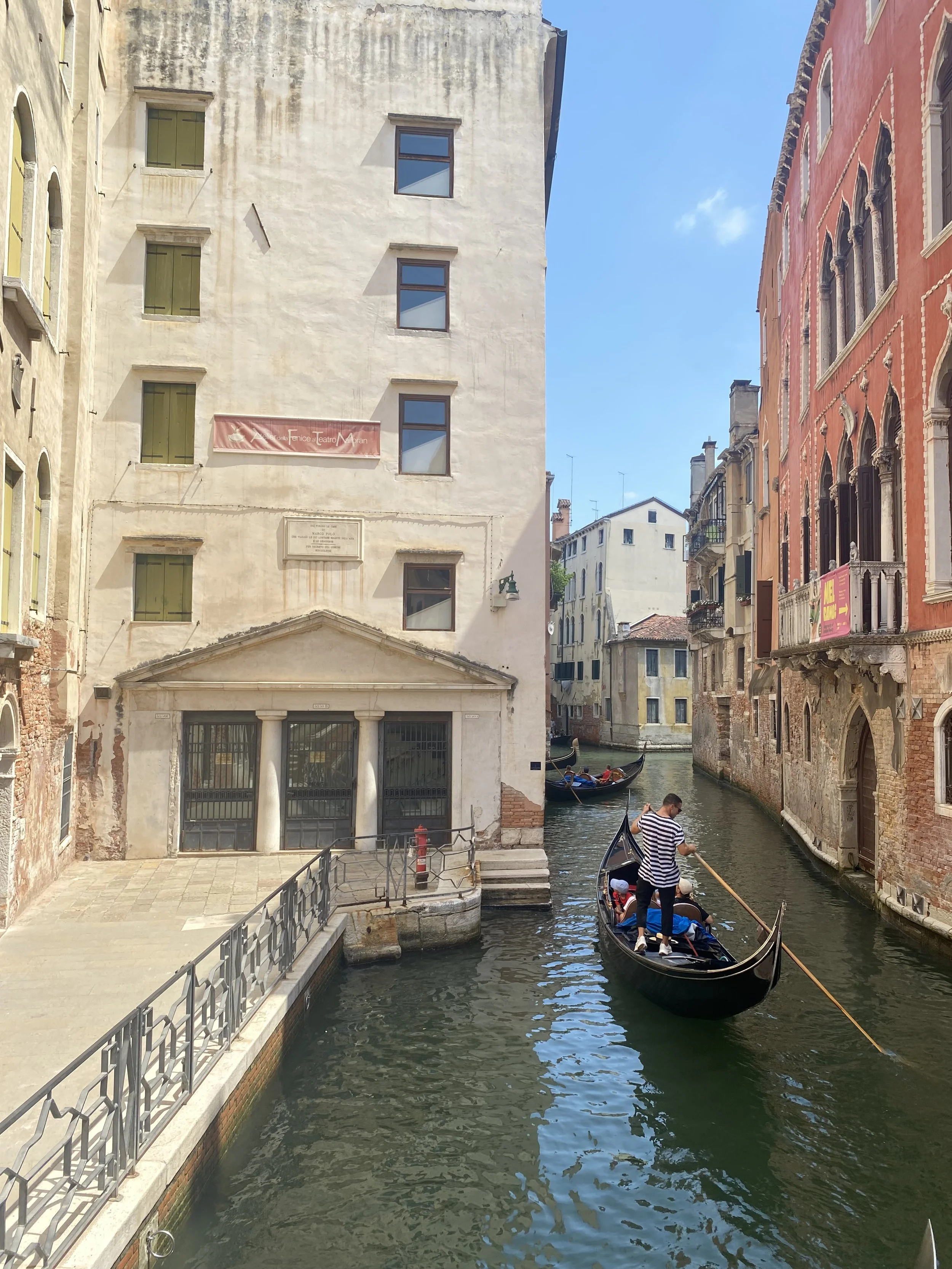 Gondola and gondolier on a canal lined with colorful buildings in Venice, Italy