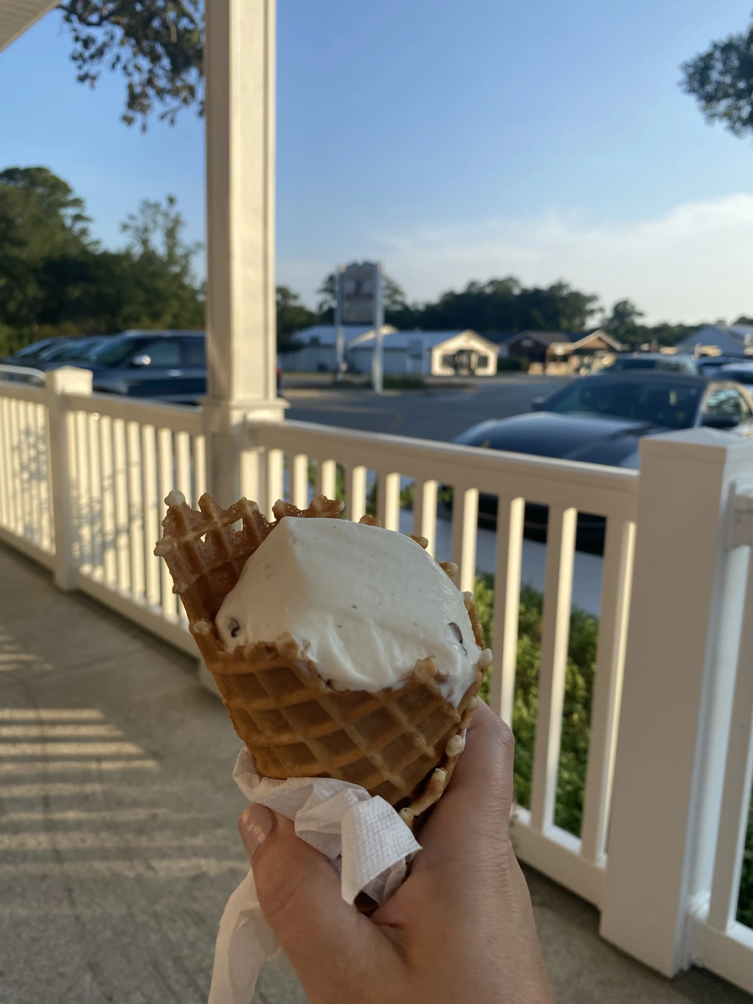 Hand holding a vanilla ice cream cone in a waffle cone at Calabash Creamery