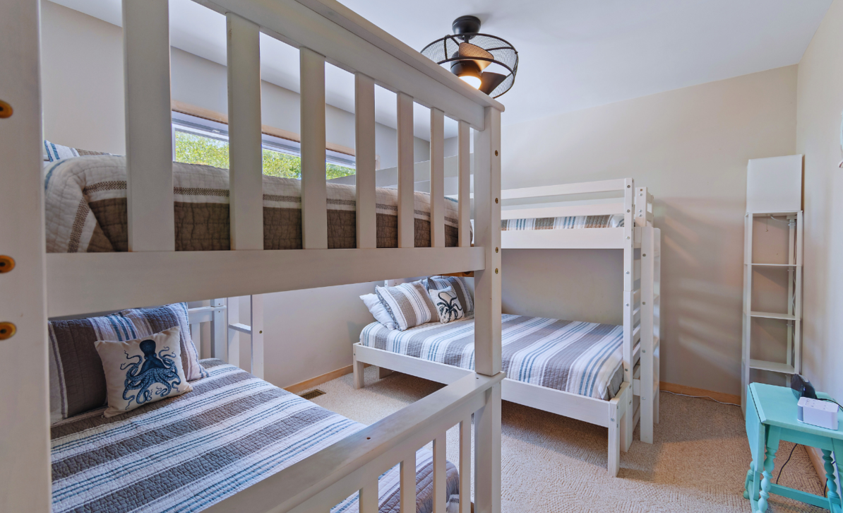 Bunk room at El Sol with white bunk beds, a twin bed, and navy-striped octopus bedding.