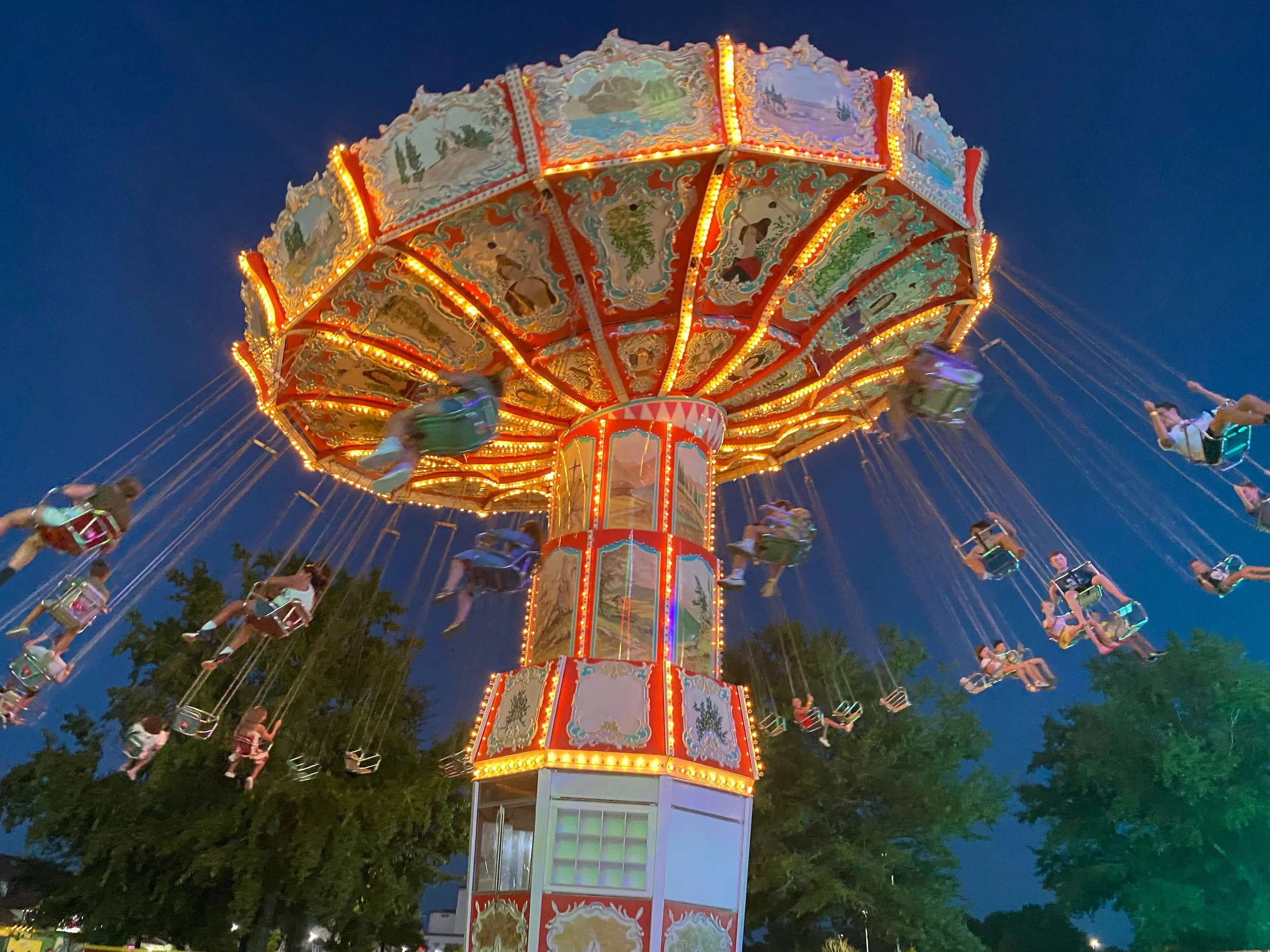 Illuminated swing ride at a carnival at night, with children riding at Broadway at the Beach in Myrtle Beach SC