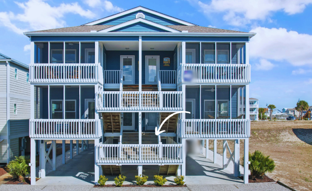 Two-story blue beach condo building home to Sol Mar with white railings and balconies, elevated on stilts, with stairs leading up to each level and located near the coast.