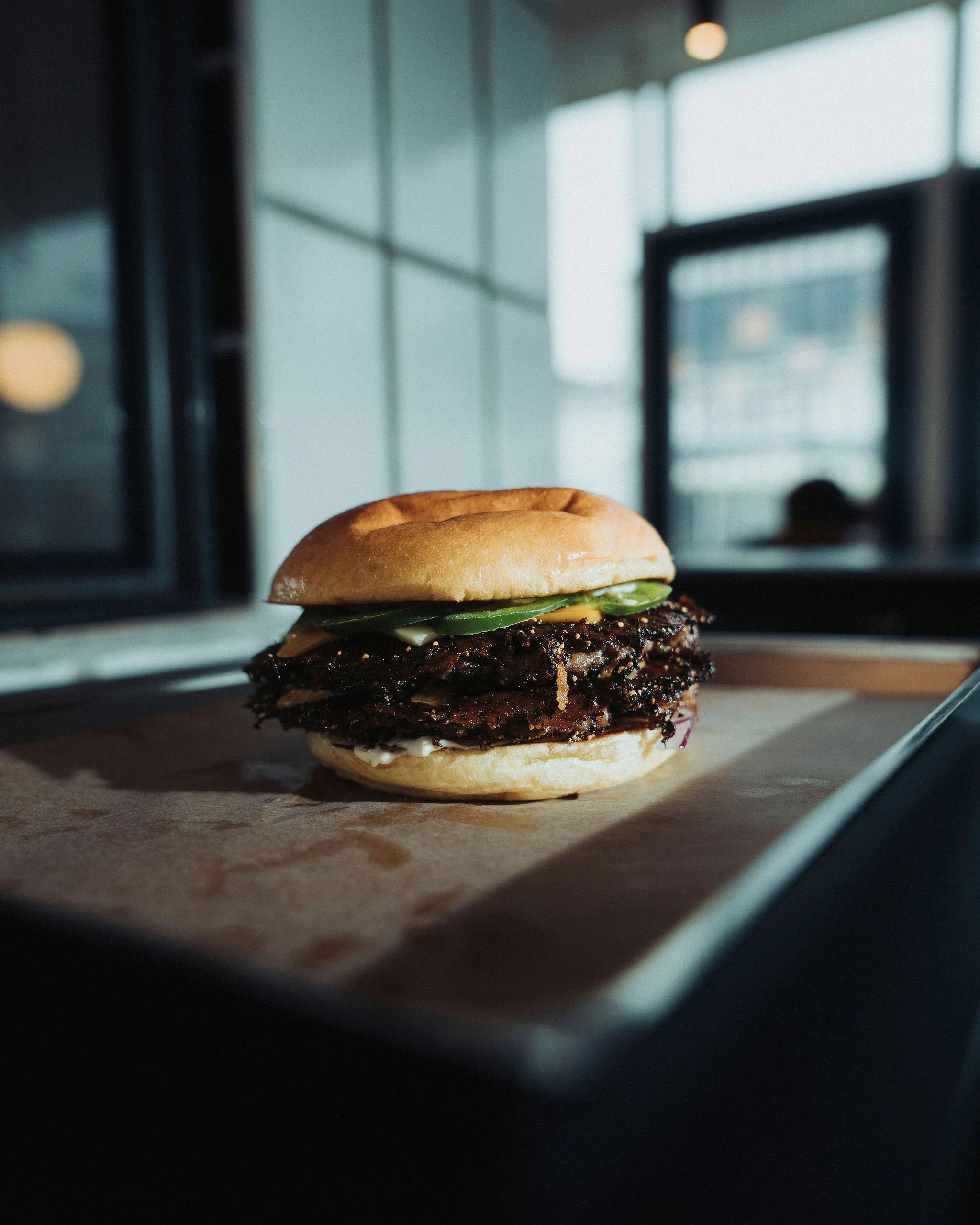 A burger with a bun, pickles and a beef patty inside an oven.