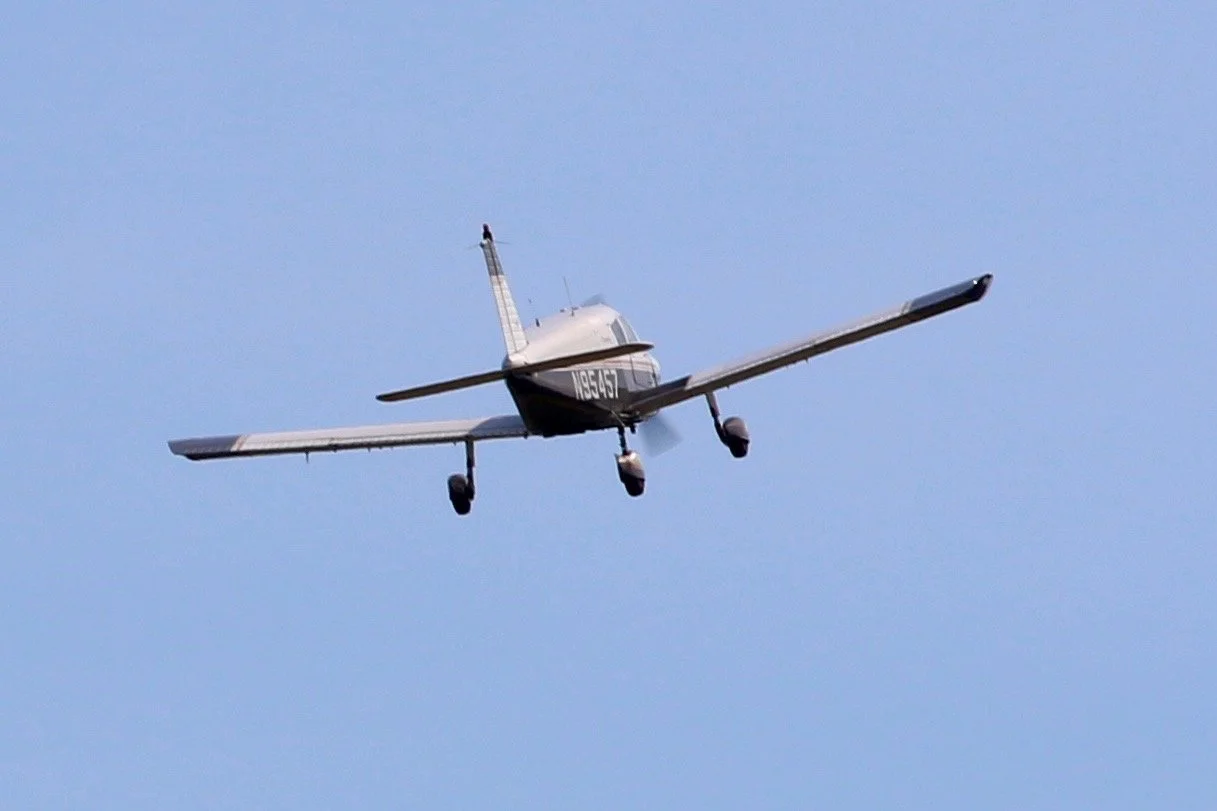 Small white and black aircraft flying in a clear blue sky.