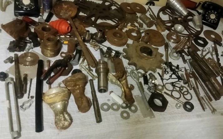 A table of salvaged metal parts, gears, tools and fittings waiting to become sculpture