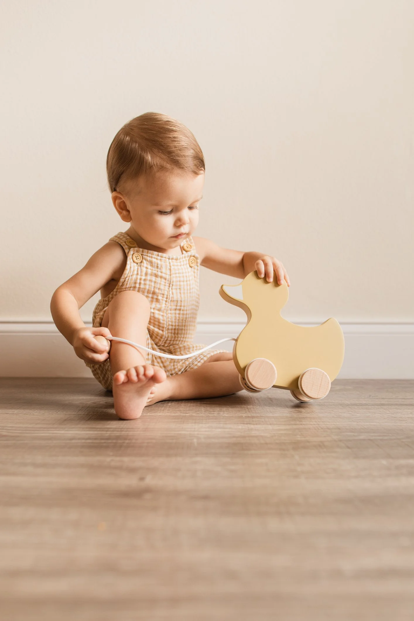 Infant exploring a wooden pull toy in a prepared Montessori environment.