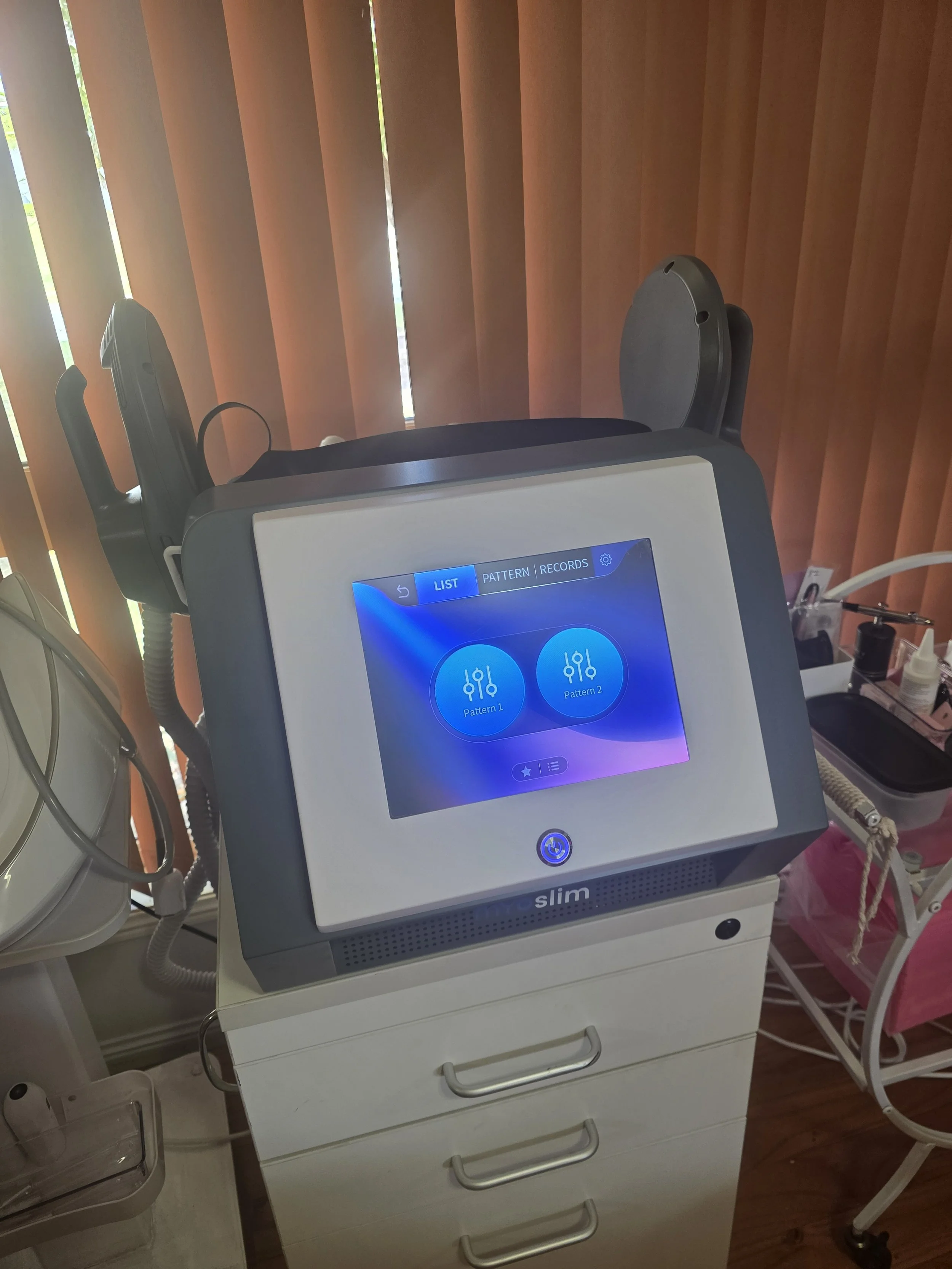 Medical device with a touchscreen display showing options for Pattern 1 and Pattern 2; situated on a white cabinet with multiple drawers, in a clinic or hospital setting.