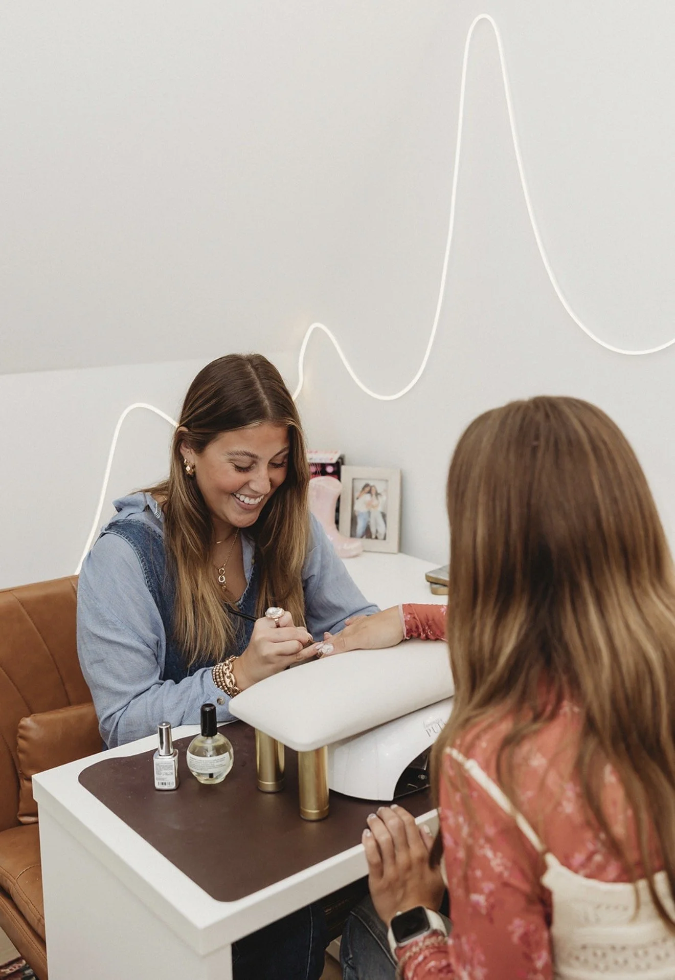 Nail technician giving a client a manicure at a salon table