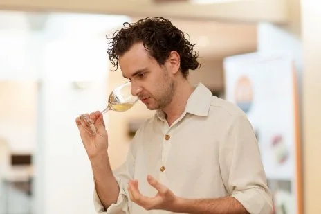 A man (Connal Finlay) tasting wine in a bright, modern kitchen.