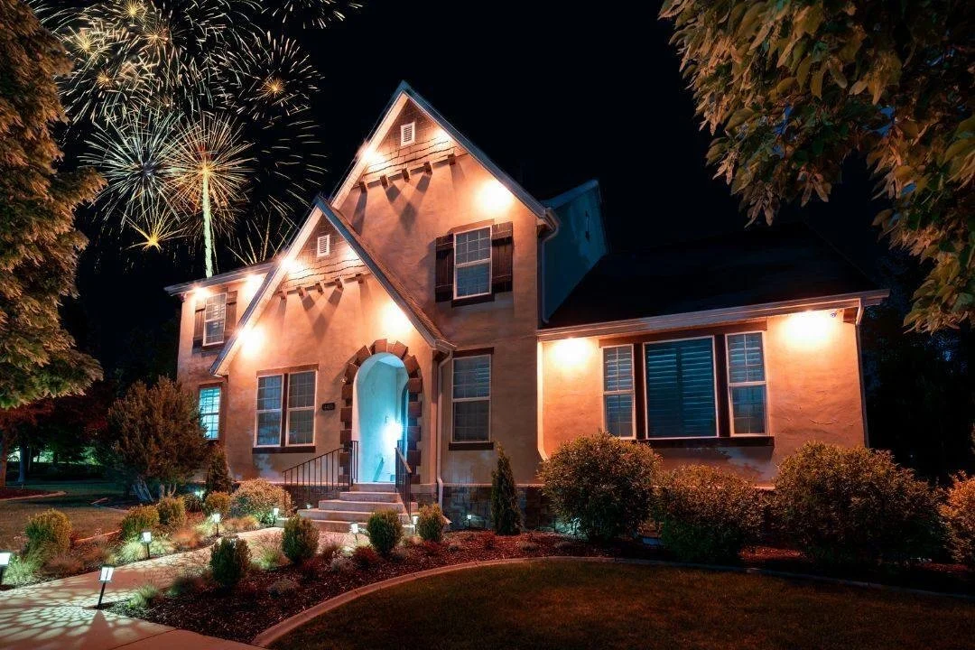 Nighttime view of a house with fireworks in the sky above.