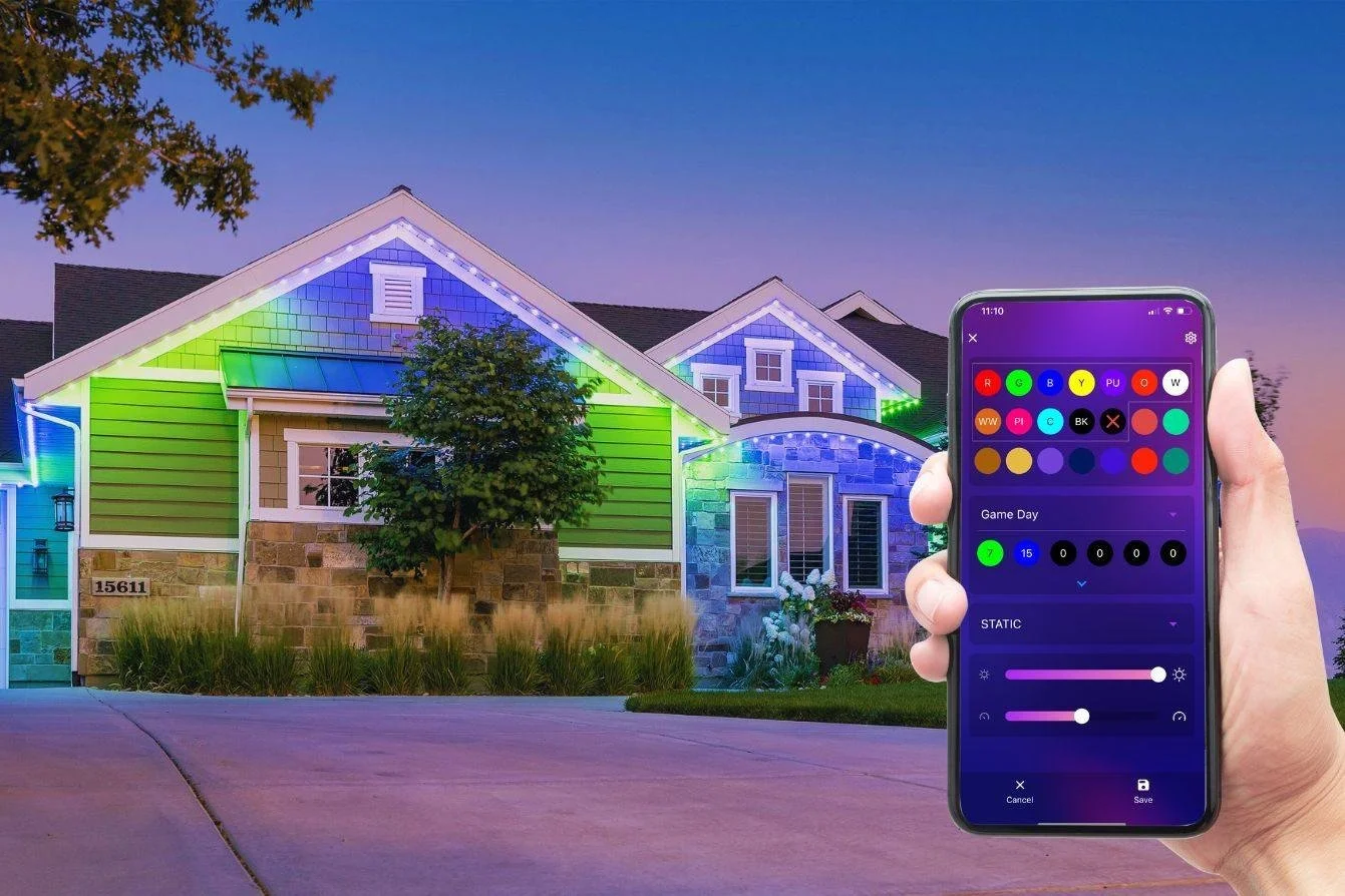 A house decorated with colorful LED house lights at twilight, with a person holding a smartphone controlling the lights.