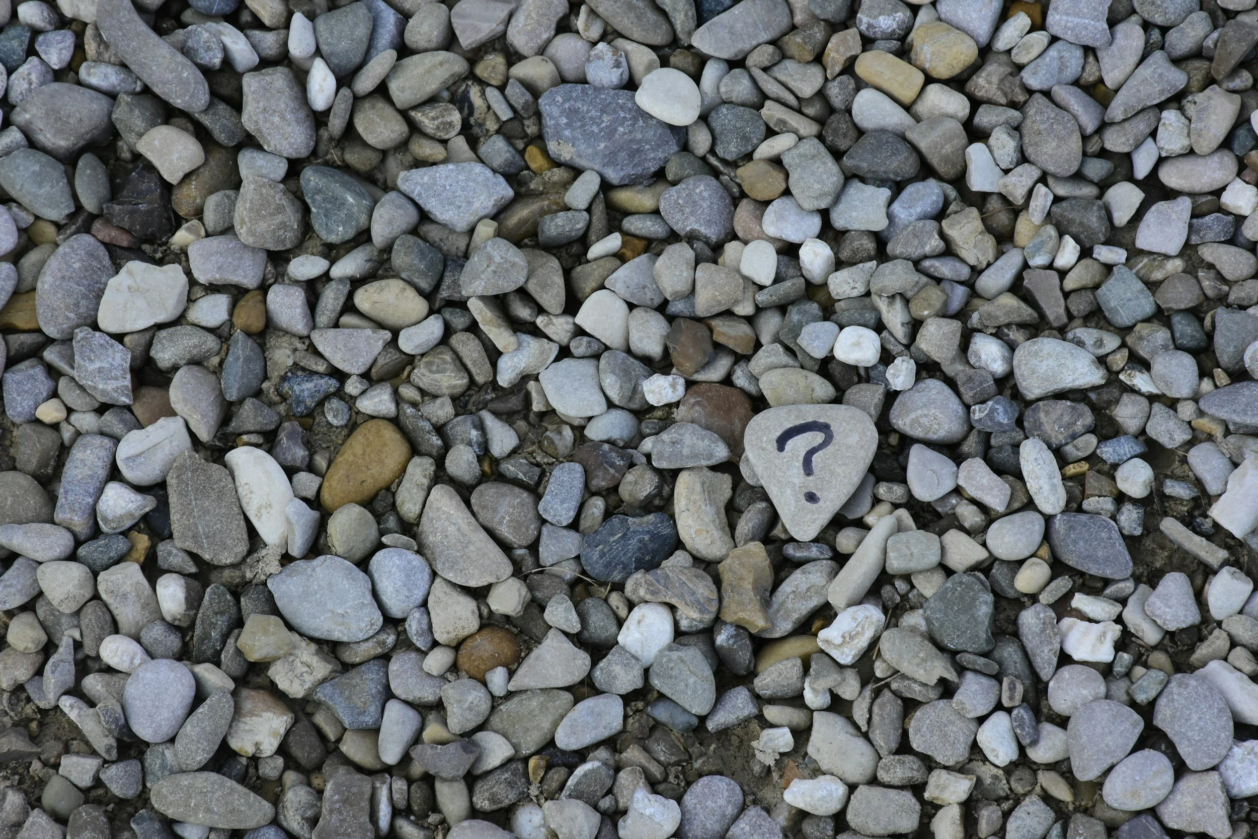 Pebble stones, with one having a questions mark.