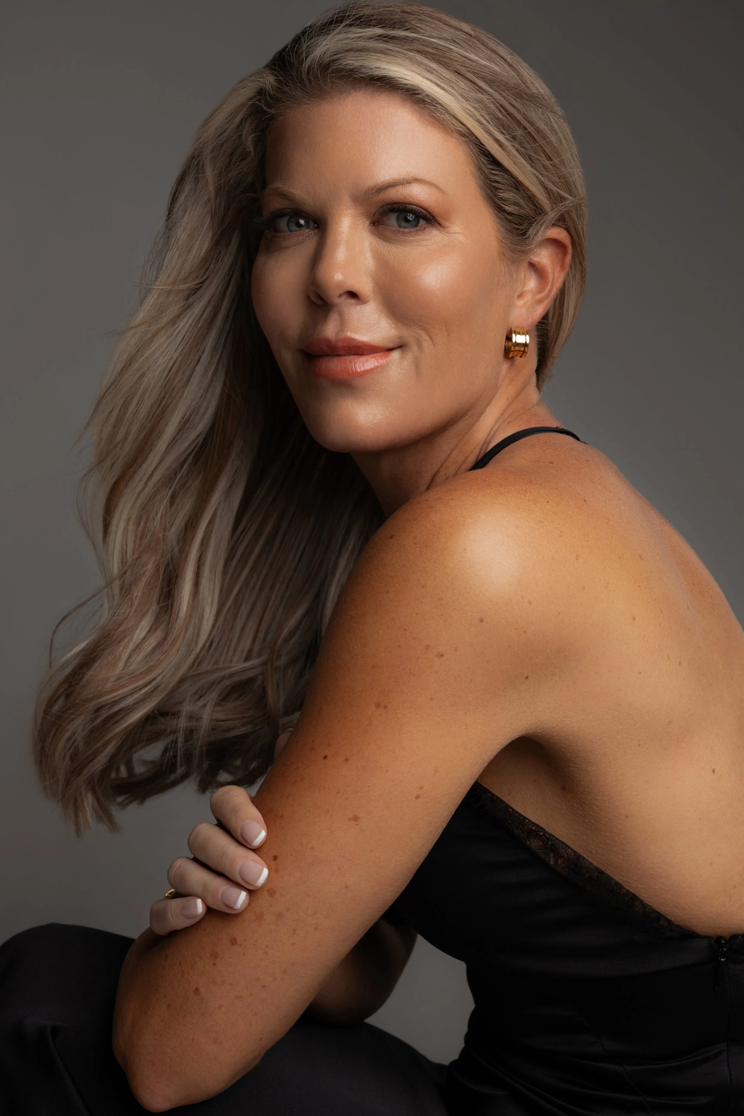 Steph Russell is a 50+ model based in Brisbane, Australia. This portfolio photo demonstrates Steph's natural beauty, with her long, wavy blonde hair, glowing skin and gold hoop earrings.