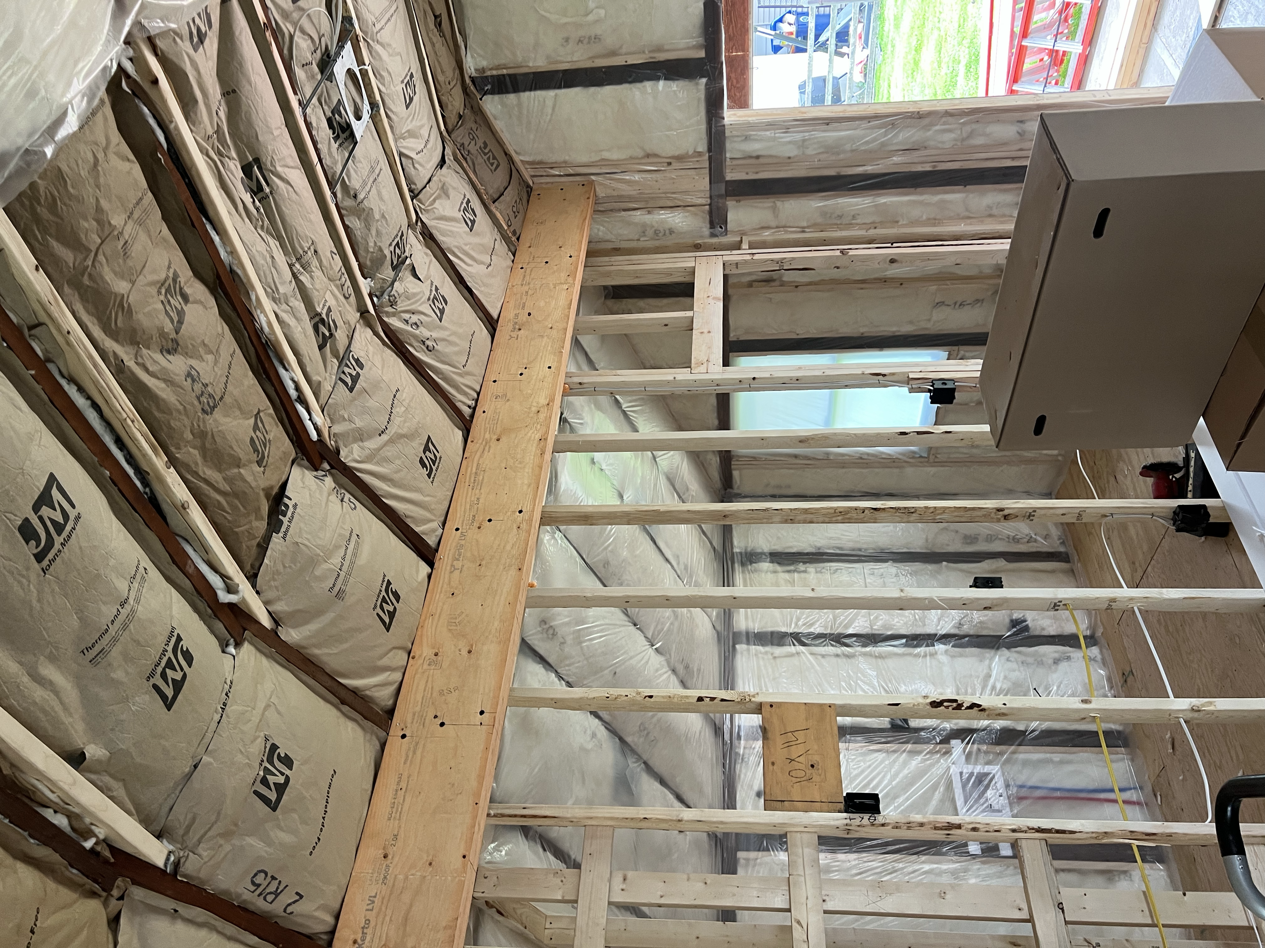 Interior of a house under construction with exposed wooden framing, insulation in the walls and ceiling, 