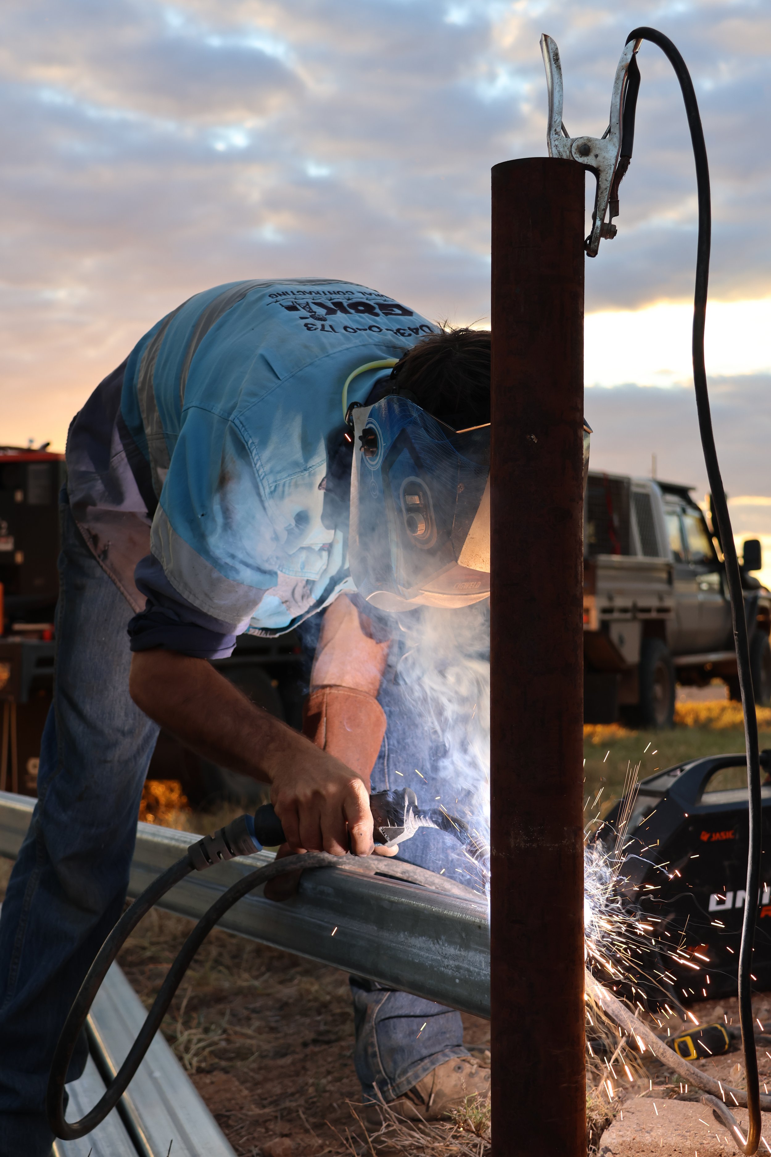 G8K Rural Co team welding metal pipes outdoors during sunset, 