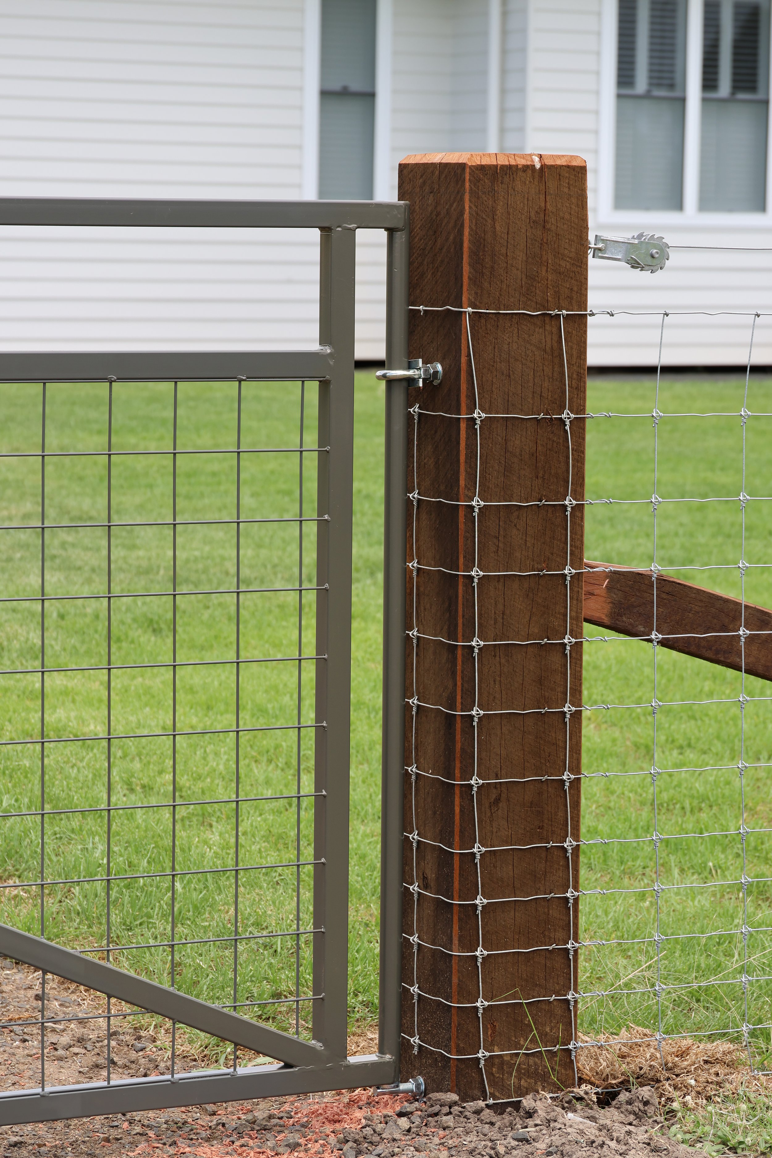 A metal gate with a wire fence attached to a wooden post fencing project by G8K Rural Co