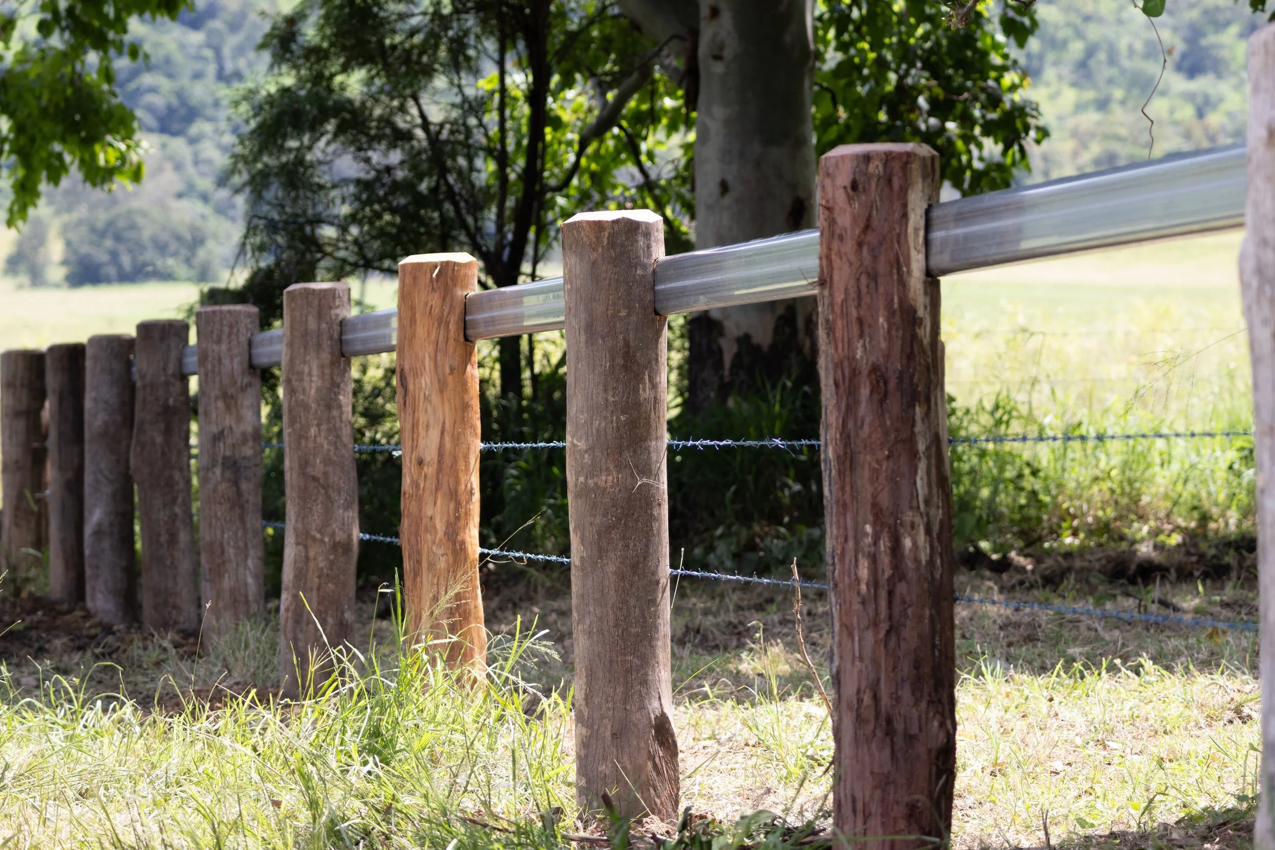A rustic wooden fence with metal rails  fencing installation in the Western Downs