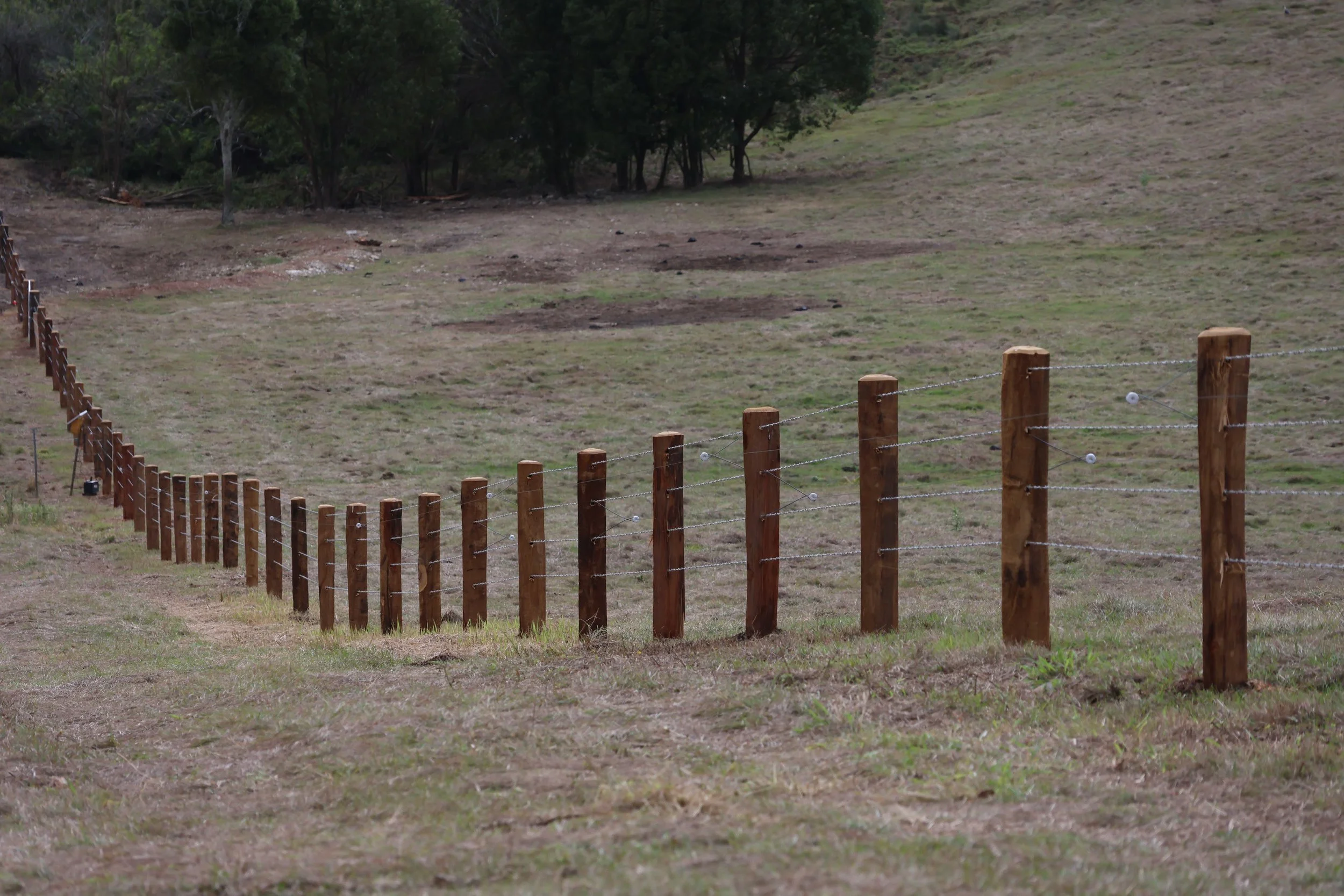 A wooden fence with barbed wire running fencing project near Dalby