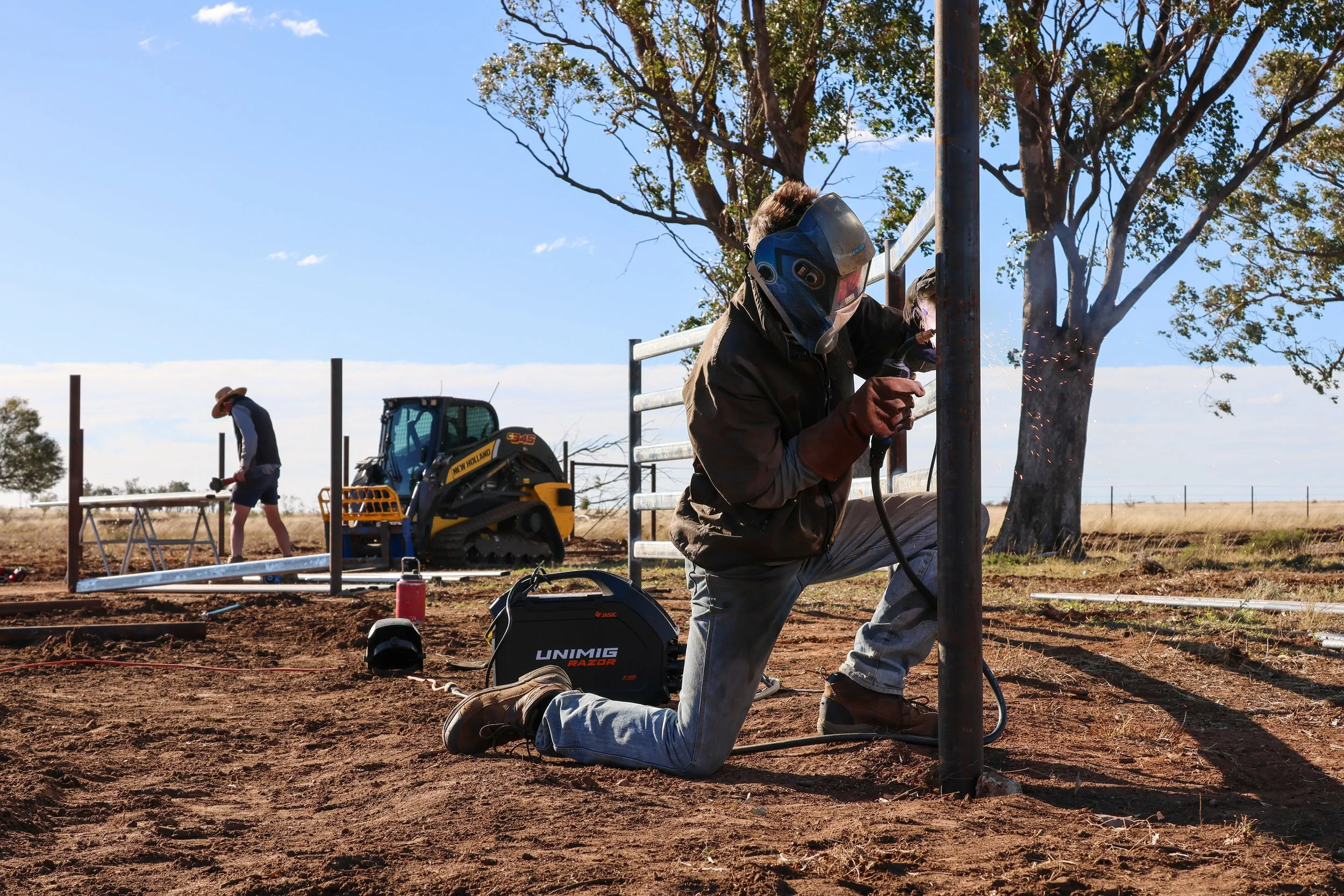 G8K Rural Co team welding a metal pole outdoors