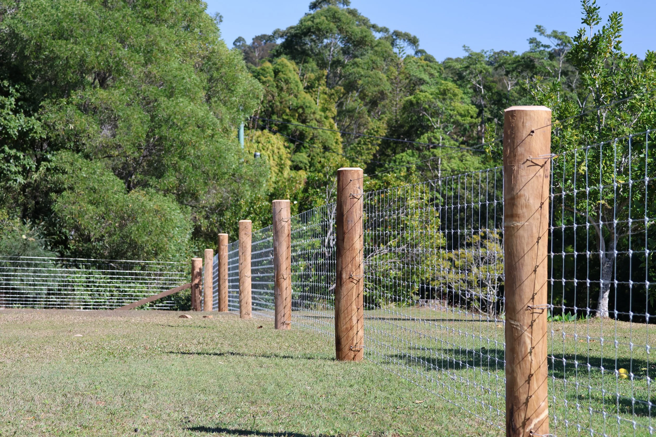 A wooden fence with wire mesh rural fencing by G8K Rural Co