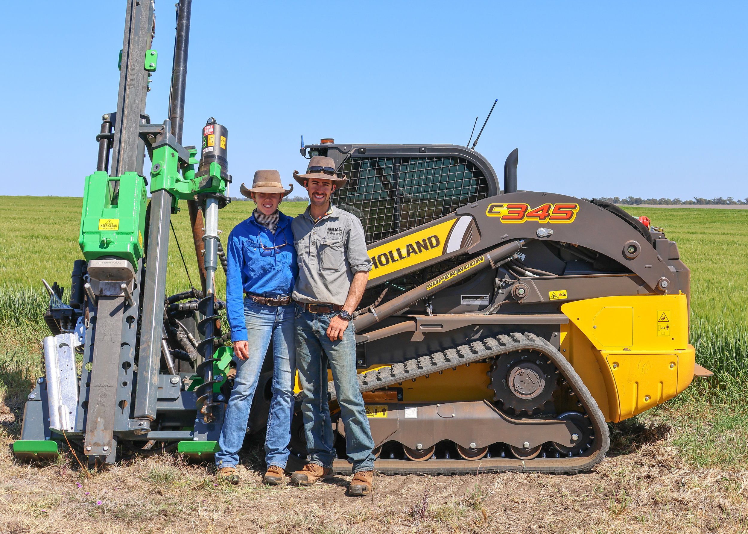 Jess and Jackson in front of a large Holland tracked agricultural machine