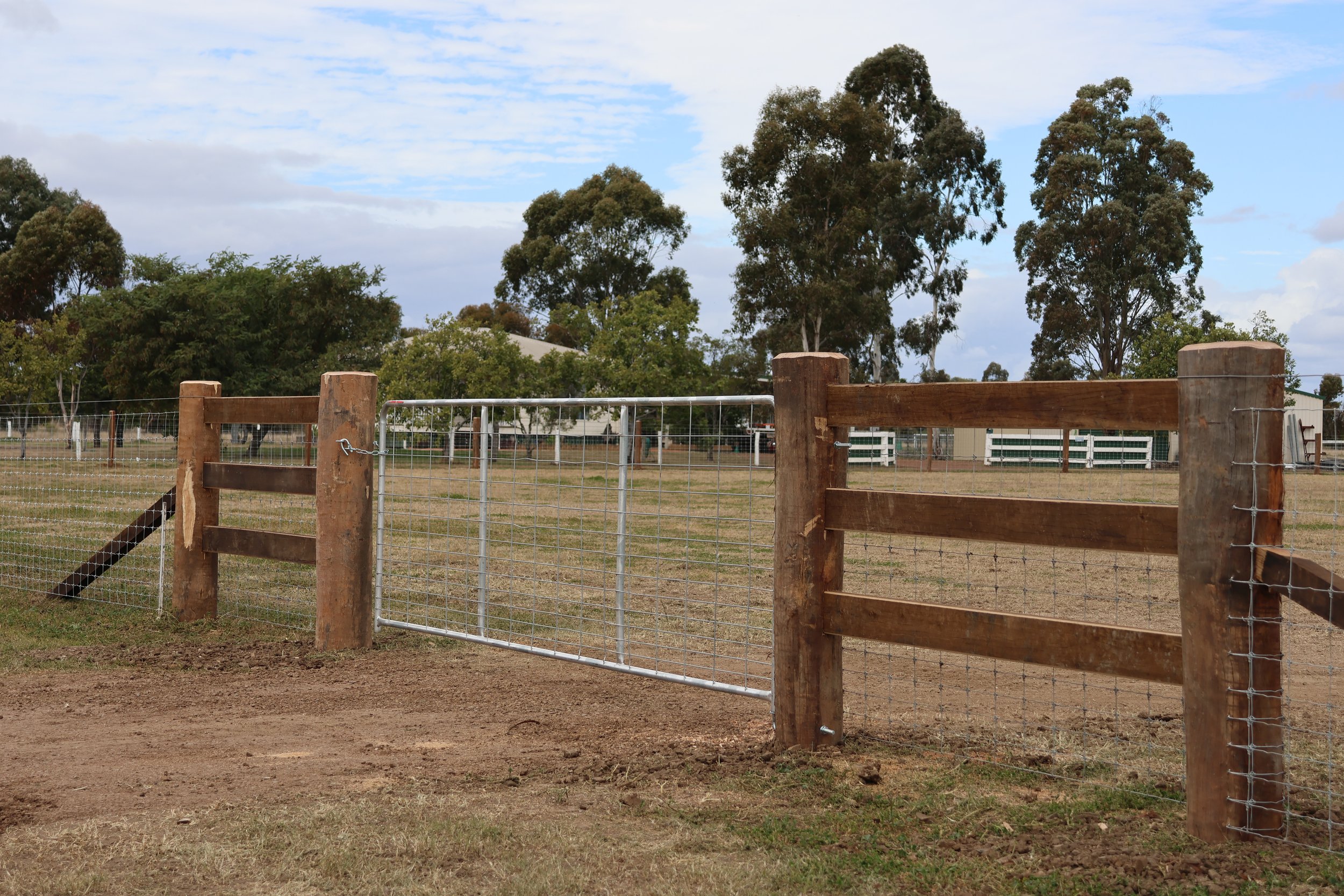 A fenced outdoor area with a wooden and wire gate,
