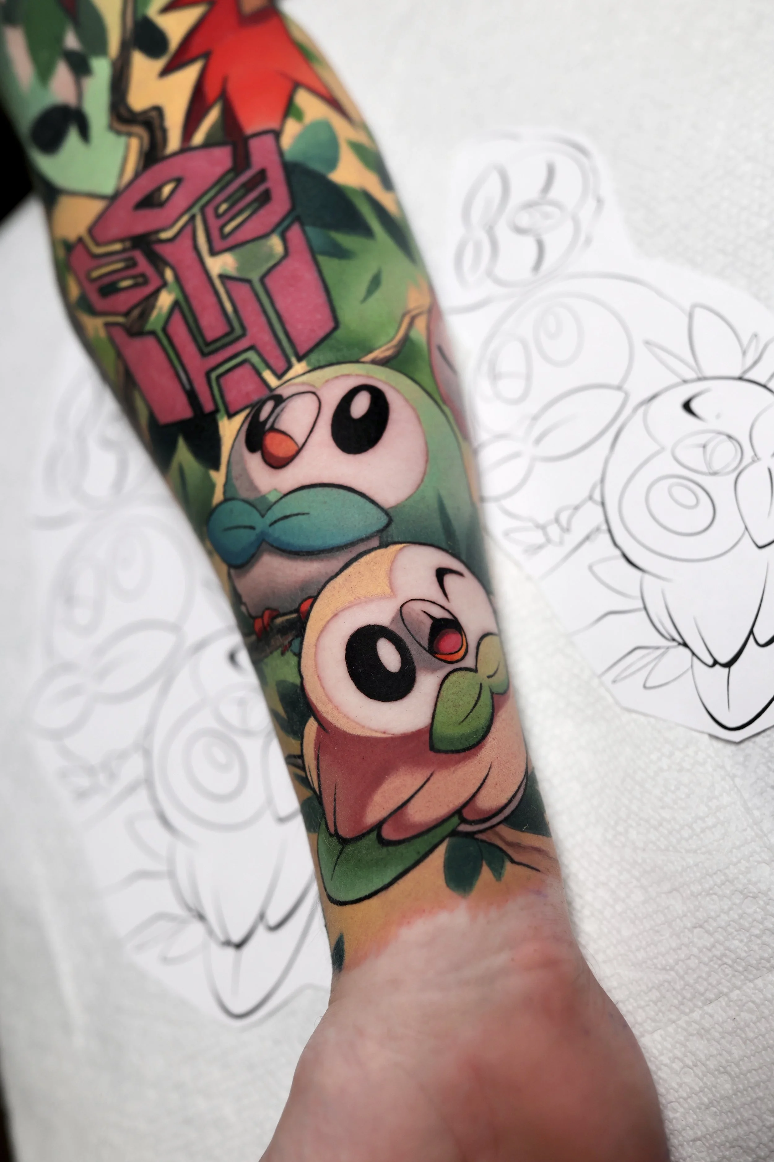 colorful tattoo of the Pokemon rowlet and a second shiny rowlet
