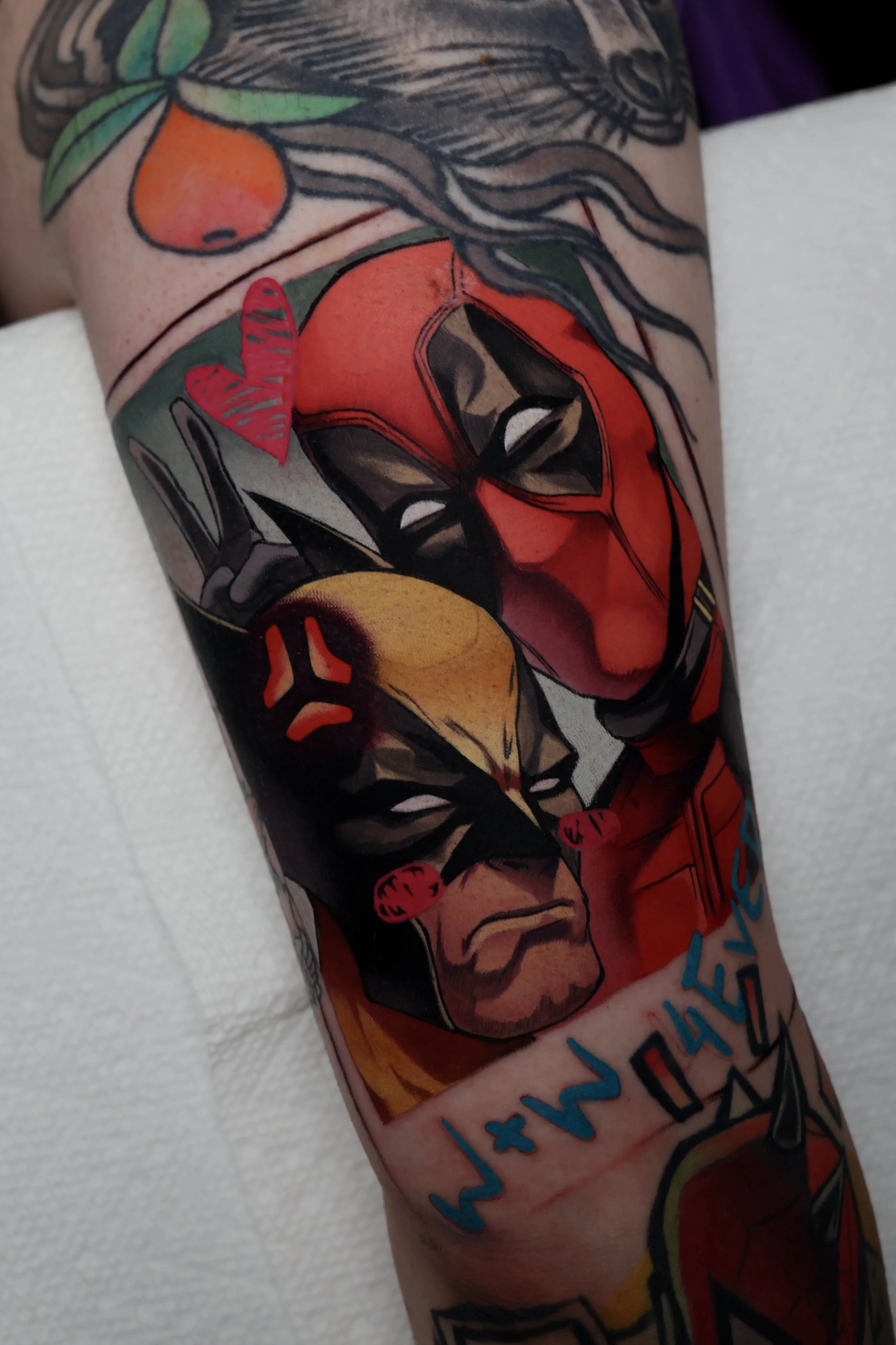 A colorful tattoo of a polaroid picture featuring Deadpool and Wolverine as friends