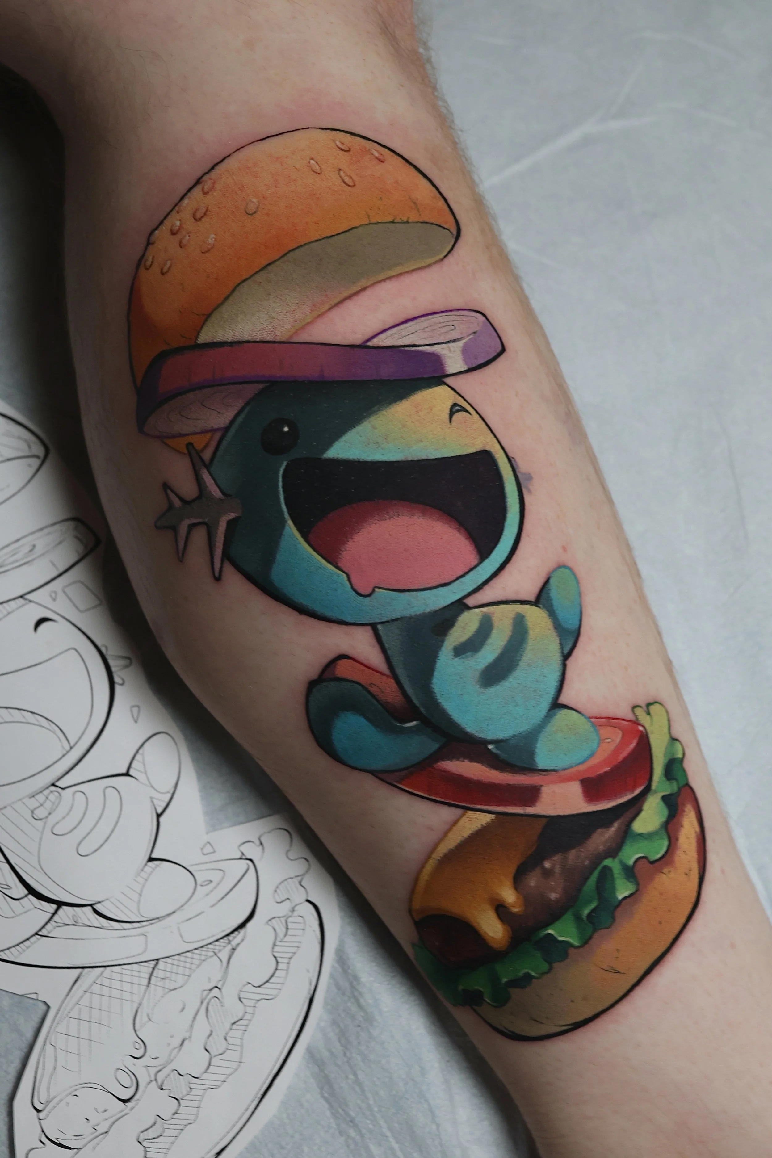 Colorful tattoo of the Pokemon Wooper inside a burger king Whopper. 