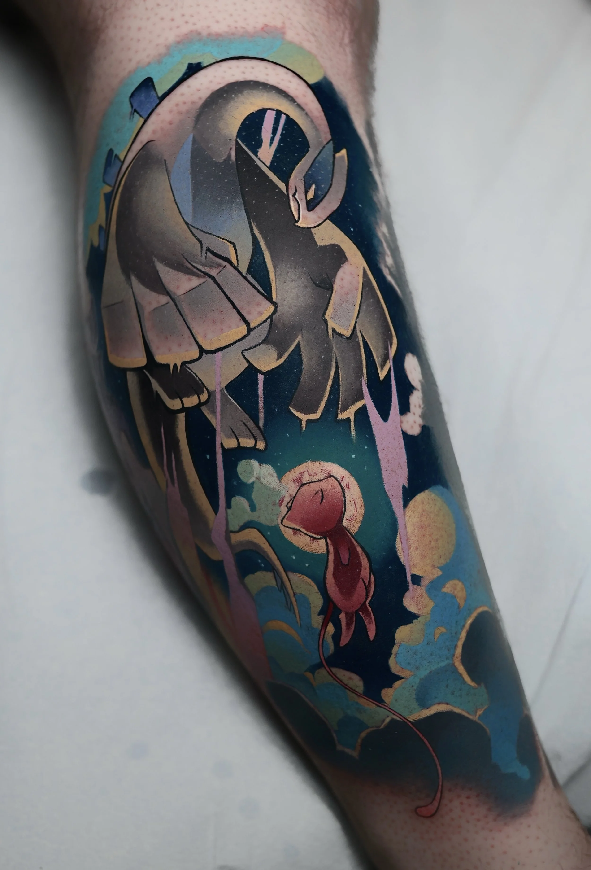 A colorful tattoo featuring a Lugia and Mew from Pokemon, flying through a cloud with a moon and starry night background.